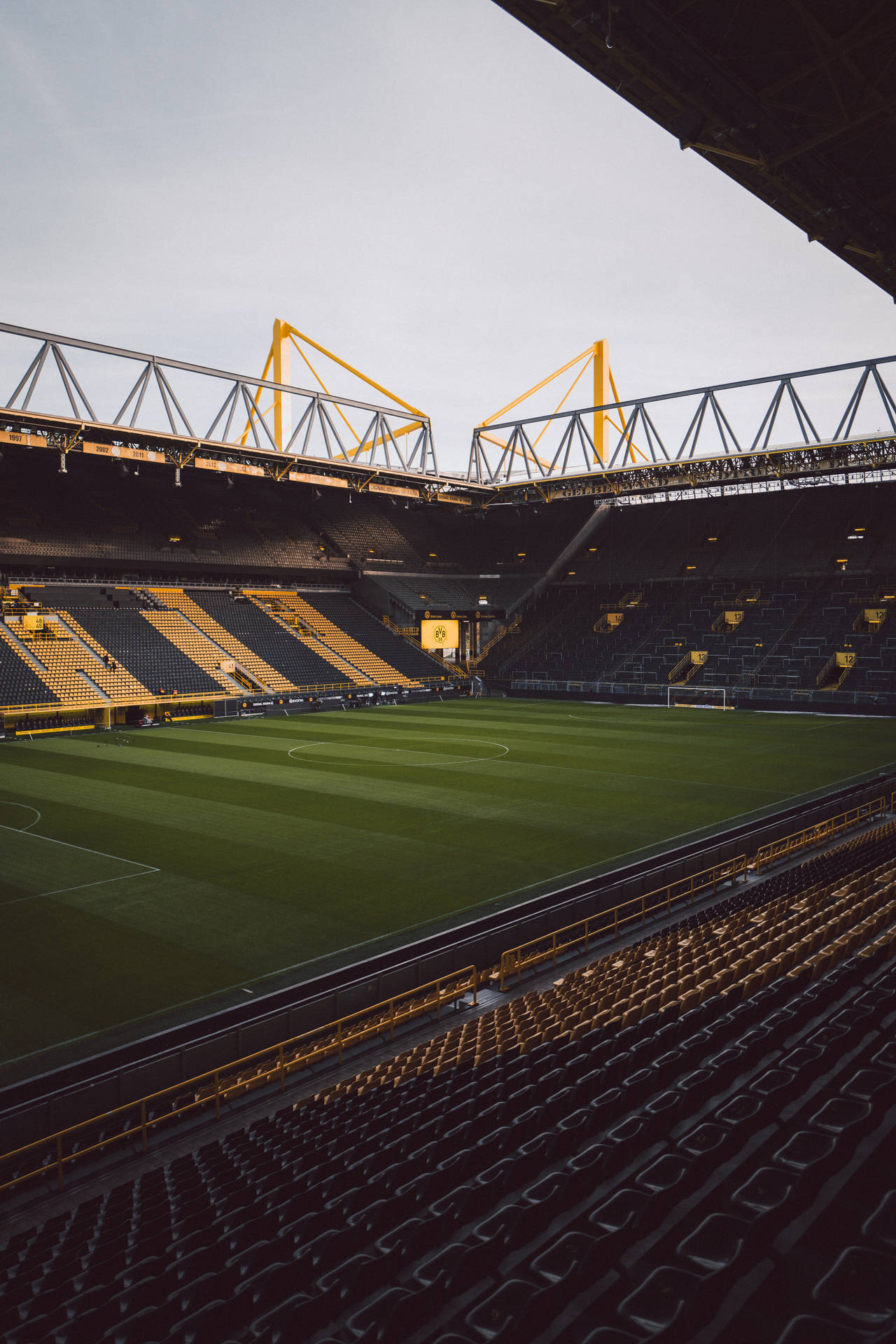 Fondo de pantalla móvil de estadio de fútbol vacío iluminado por la luz del sol.