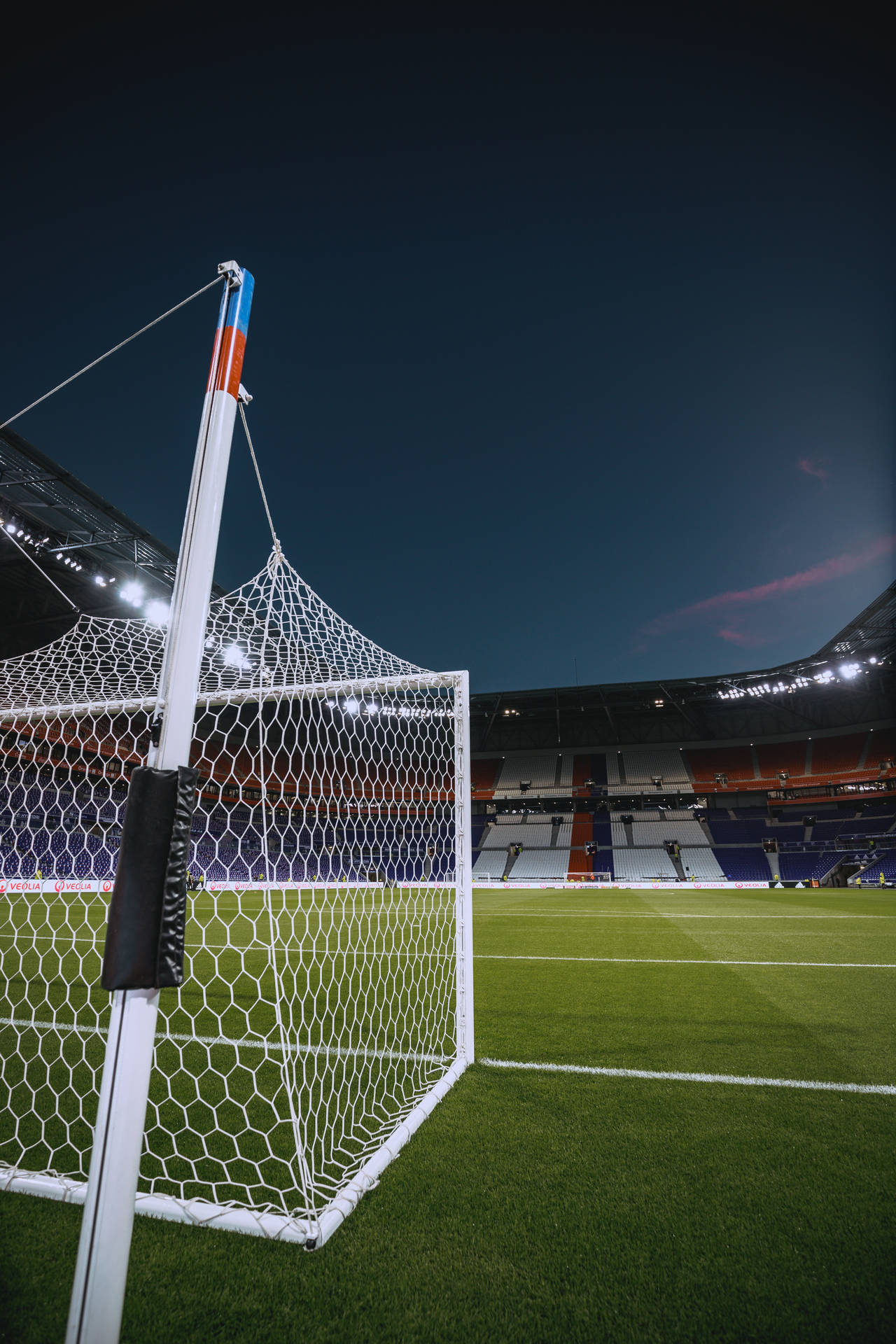 Fondo de pantalla móvil de estadio de fútbol con poste de gol y cielo nocturno.