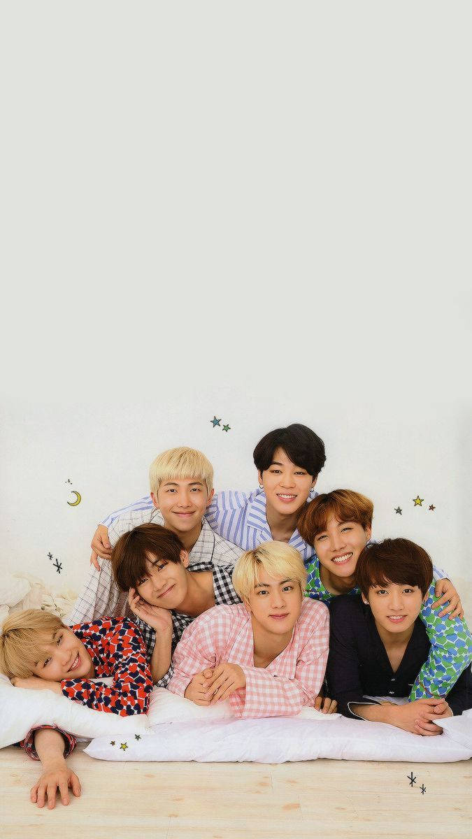 Fondo de pantalla de BTS acostados juntos en la cama sonriendo.