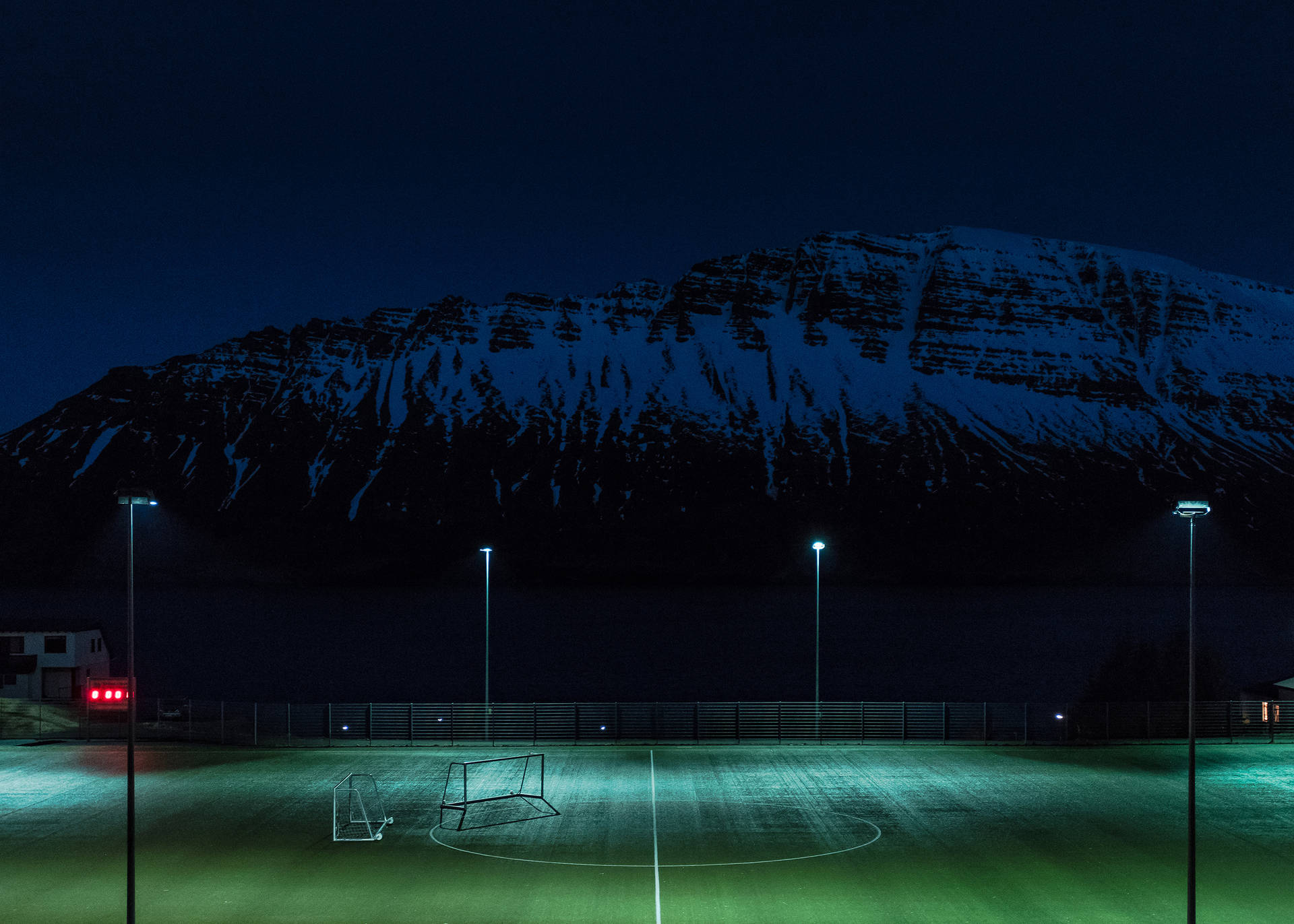 Fondo de escritorio de campo de fútbol nocturno iluminado por postes de luz.