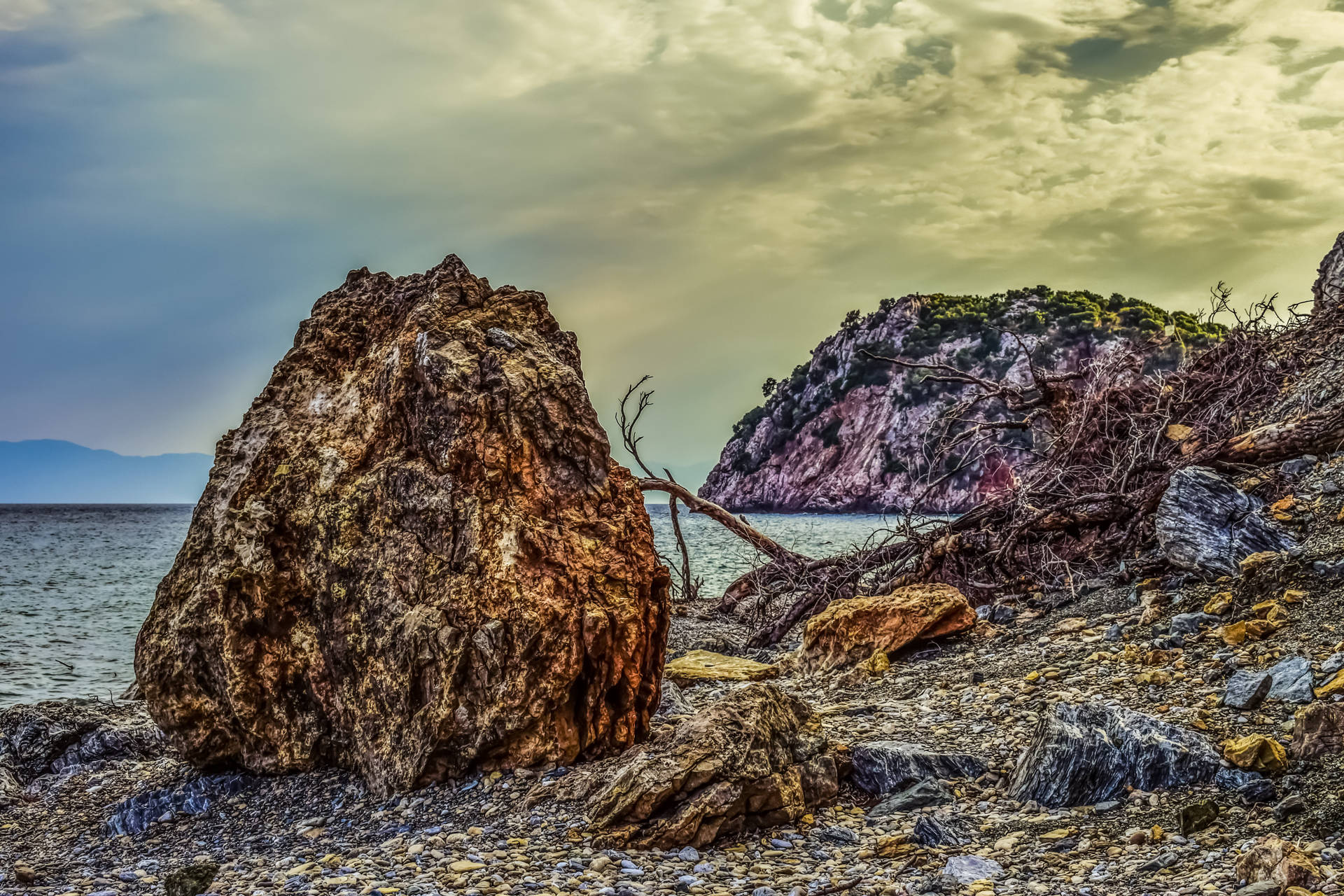 Fondo de pantalla de playa rocosa y sombría.
