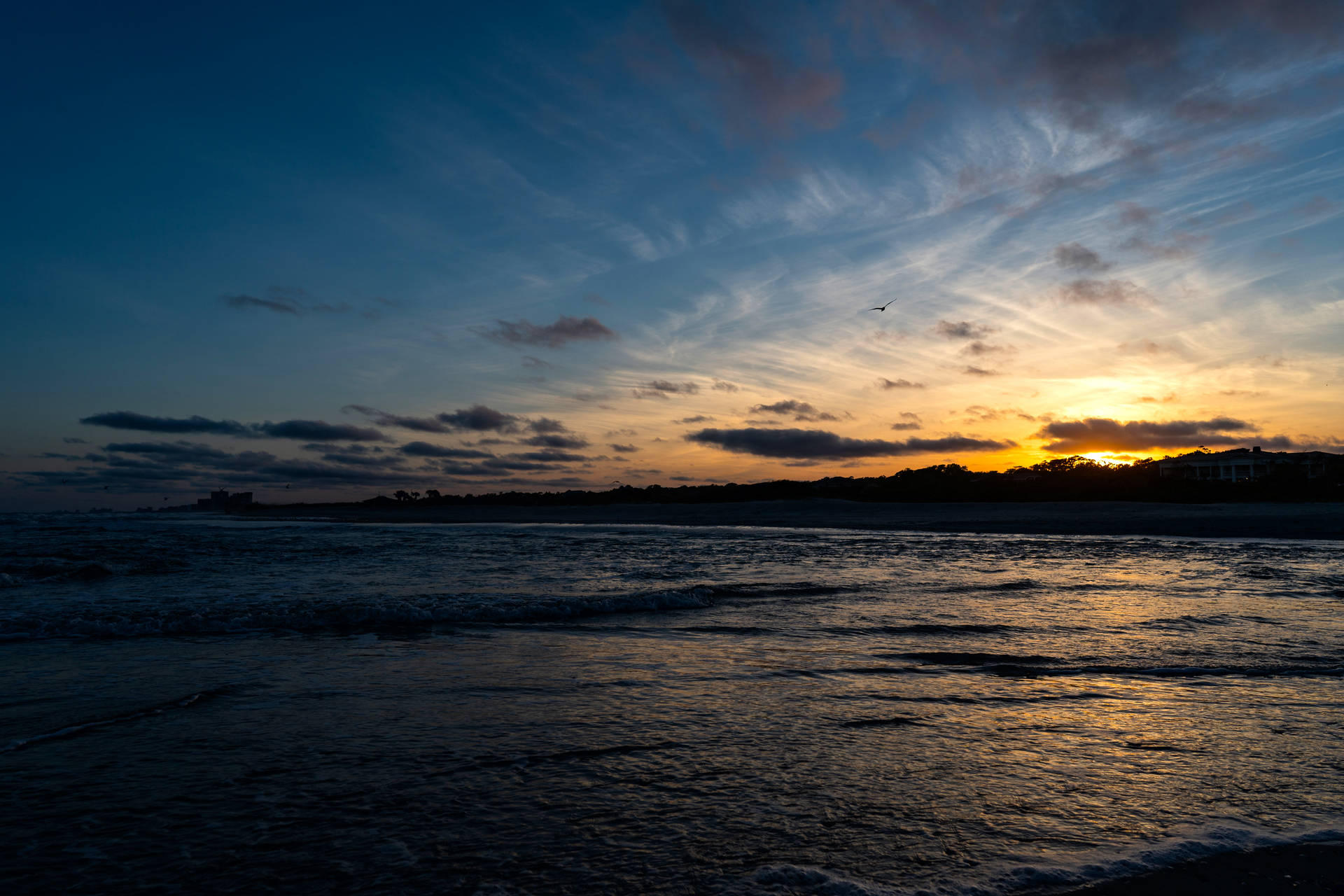 Atardecer en el mar con aguas claras y un cielo azul.