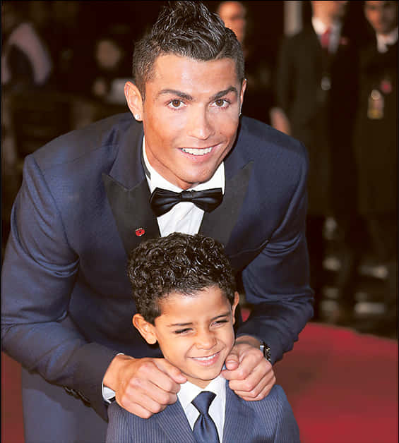 Cristiano Ronaldo sonriendo con un niño en un evento Fondos de pantalla