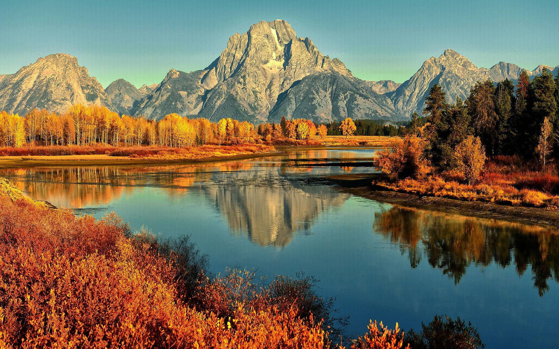 Disfruta del pintoresco paisaje otoñal de un lago rodeado de montañas. Fondos de pantalla