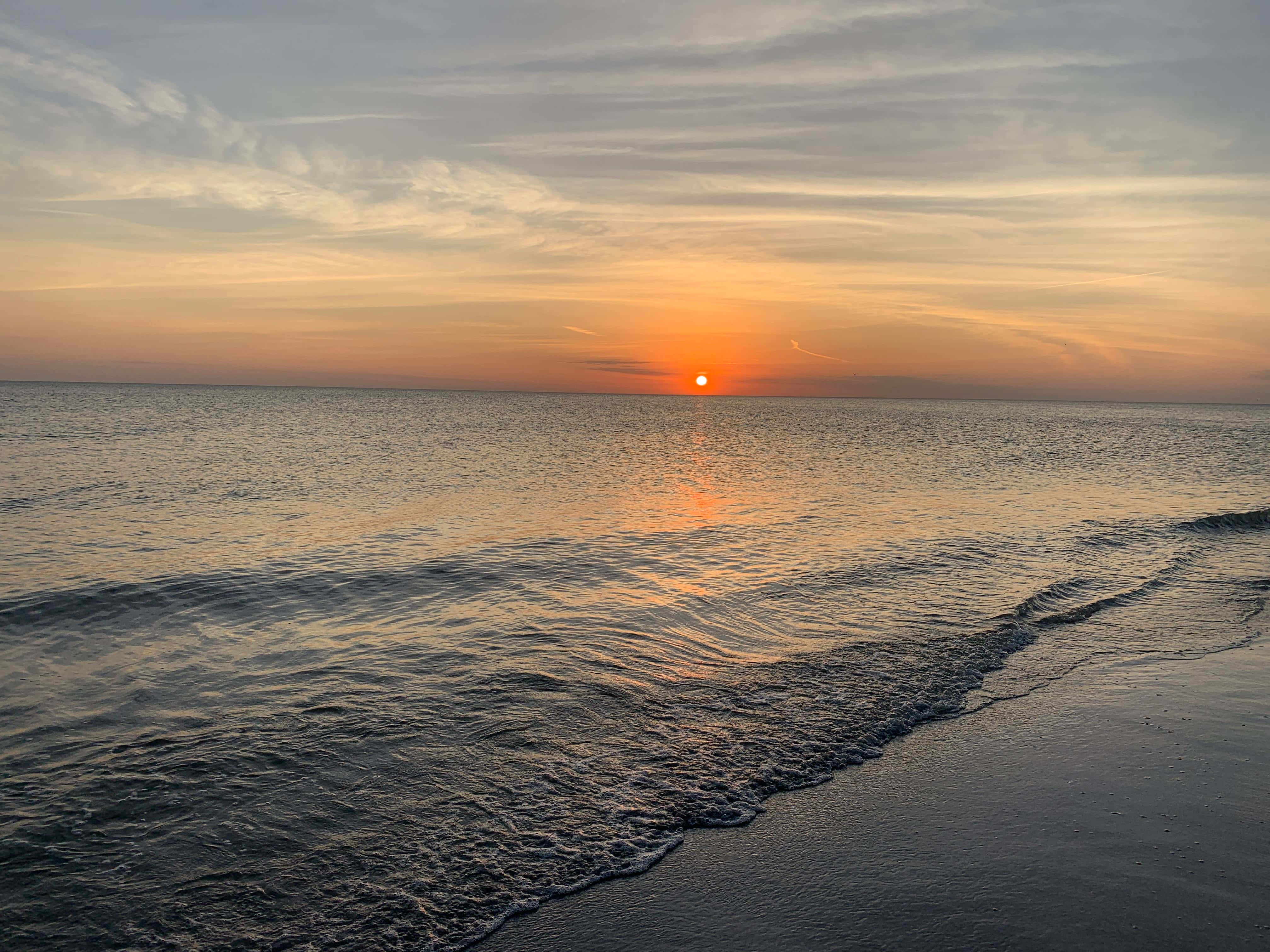 Disfruta los colores brillantes de un atardecer en la playa Fondos de pantalla