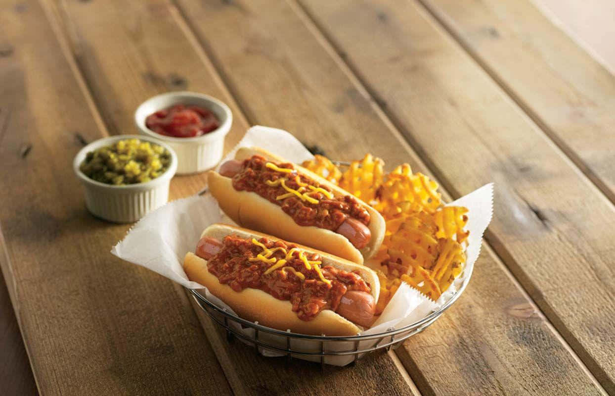 dos hot dogs en una canasta con papas fritas y chile Fondos de pantalla