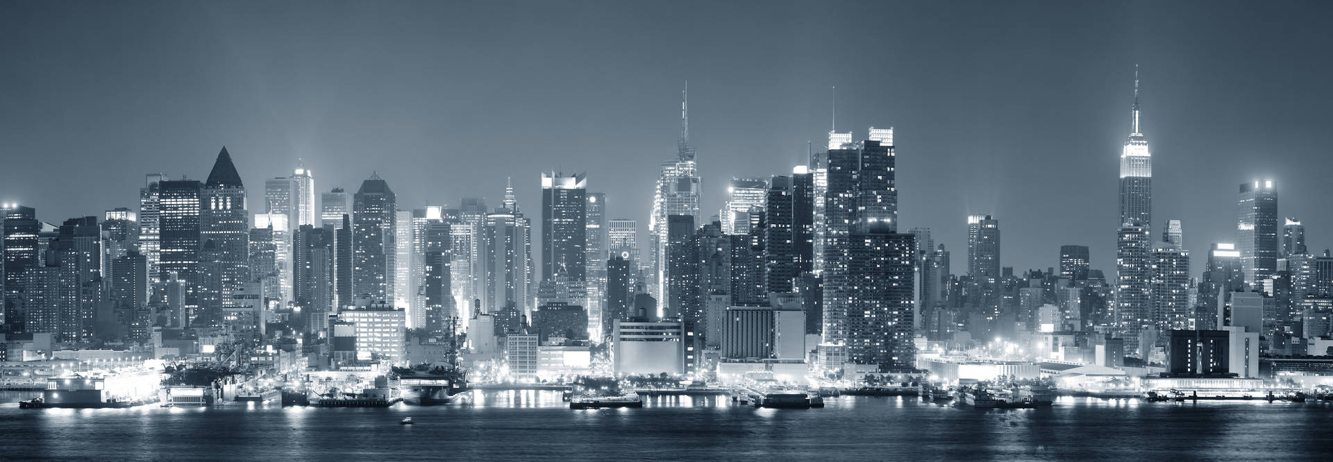 Edificios urbanos con luces brillantes en la noche, fondo de pantalla en blanco y negro para dos monitores