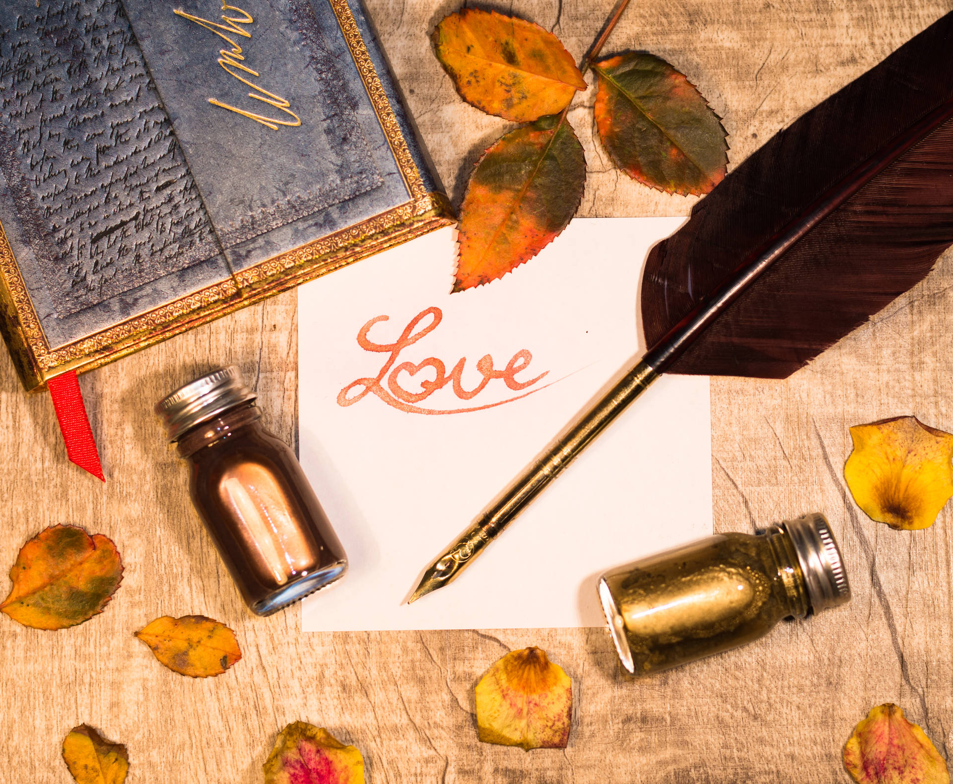 Inscripción naranja "Amor" escrita en un trozo de papel blanco con pluma y frascos de tinta sobre una mesa de madera. Carta de amor para el Día de San Valentín.