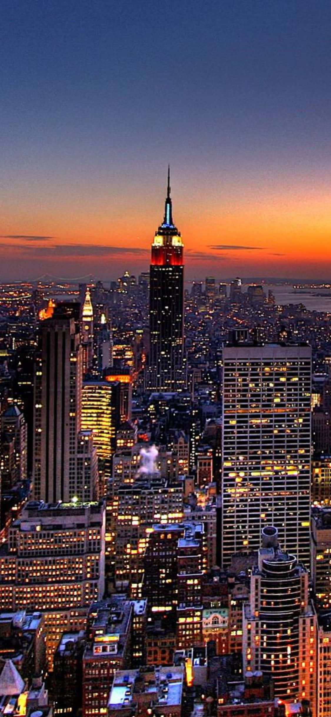 El horizonte de Nueva York brilla con la silueta de un iPhone X Fondos de pantalla