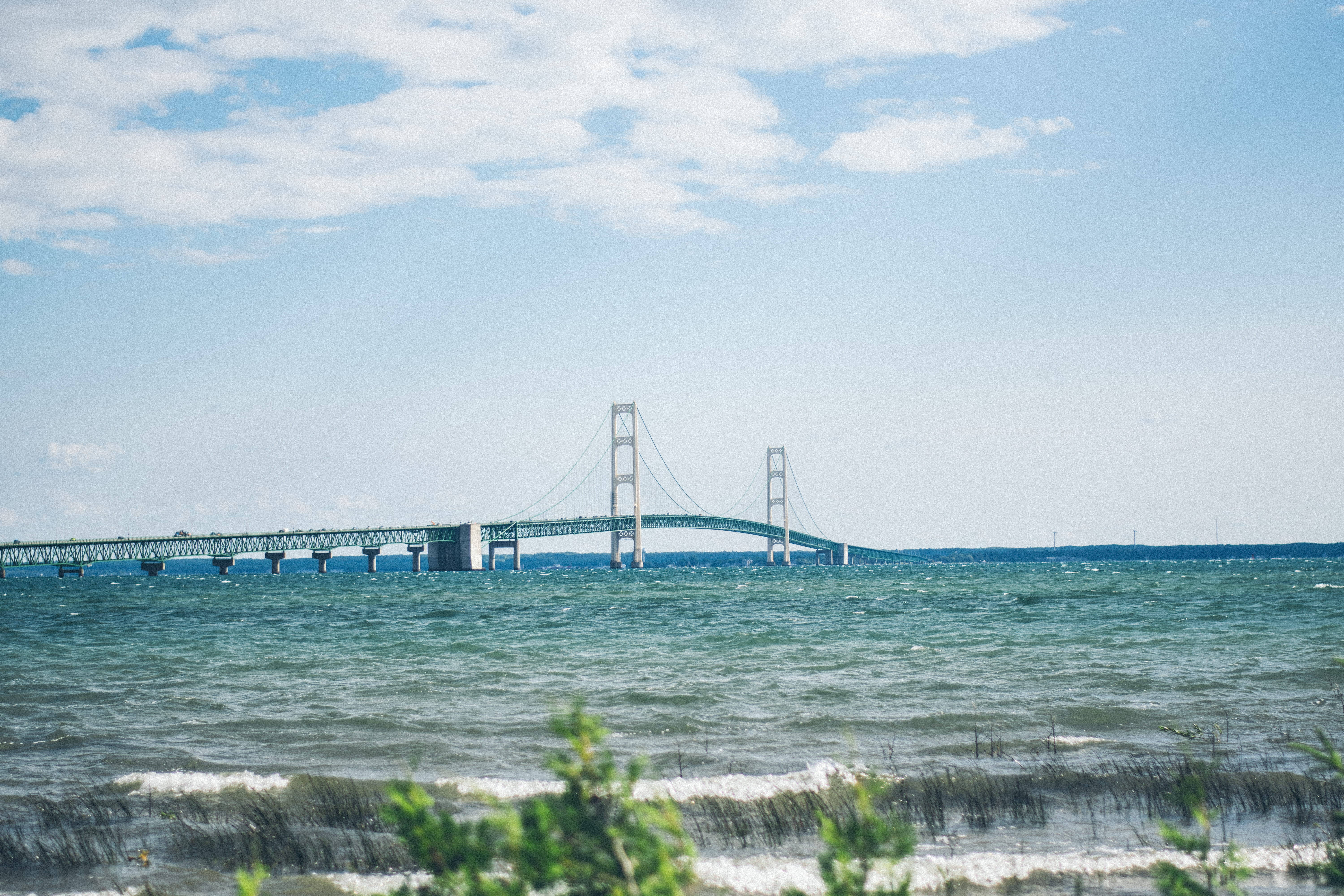 El majestuoso puente Mackinac extendiéndose sobre las serenas aguas azules Fondos de pantalla