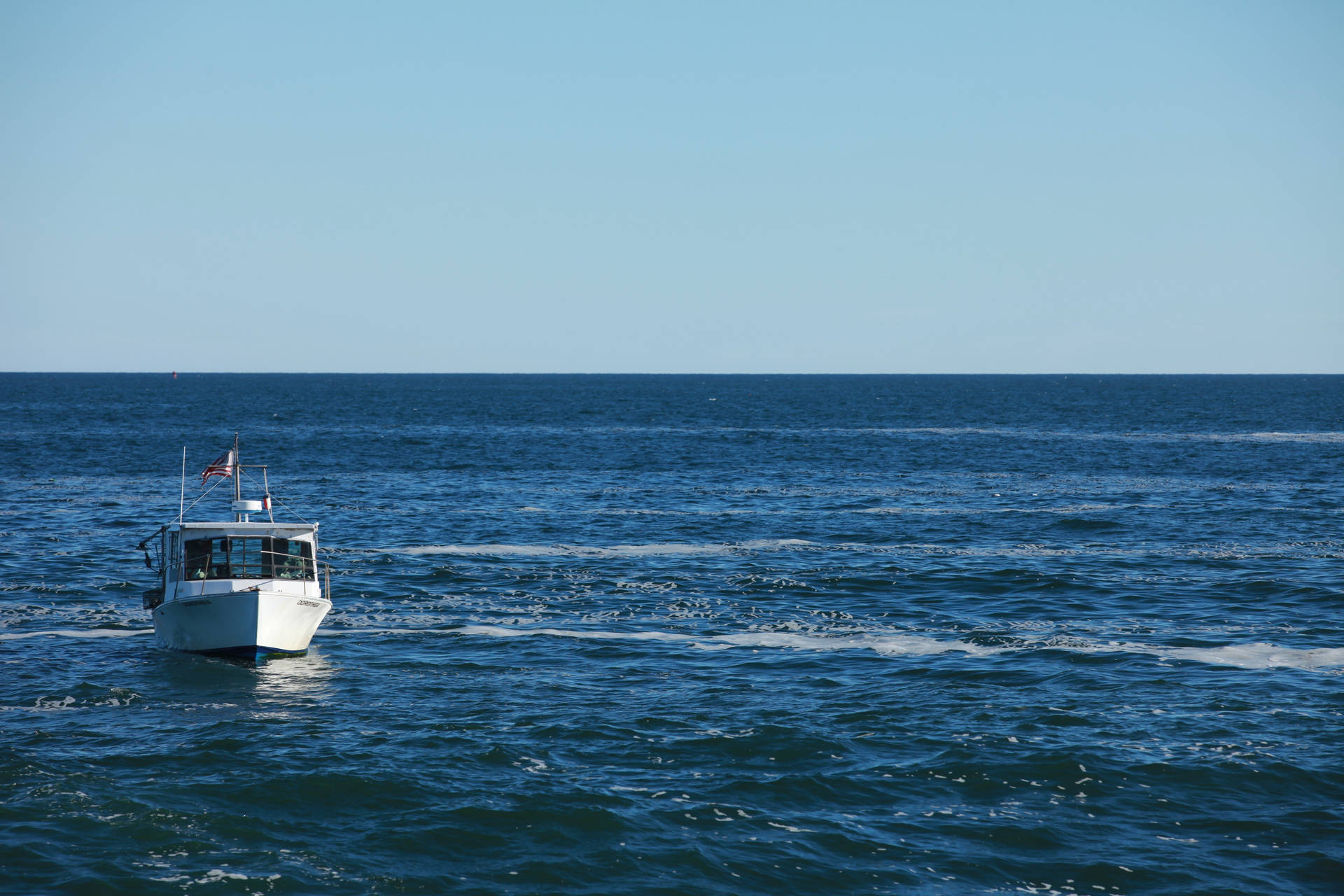 Barco en un gran océano azul con olas en un clima brillante.