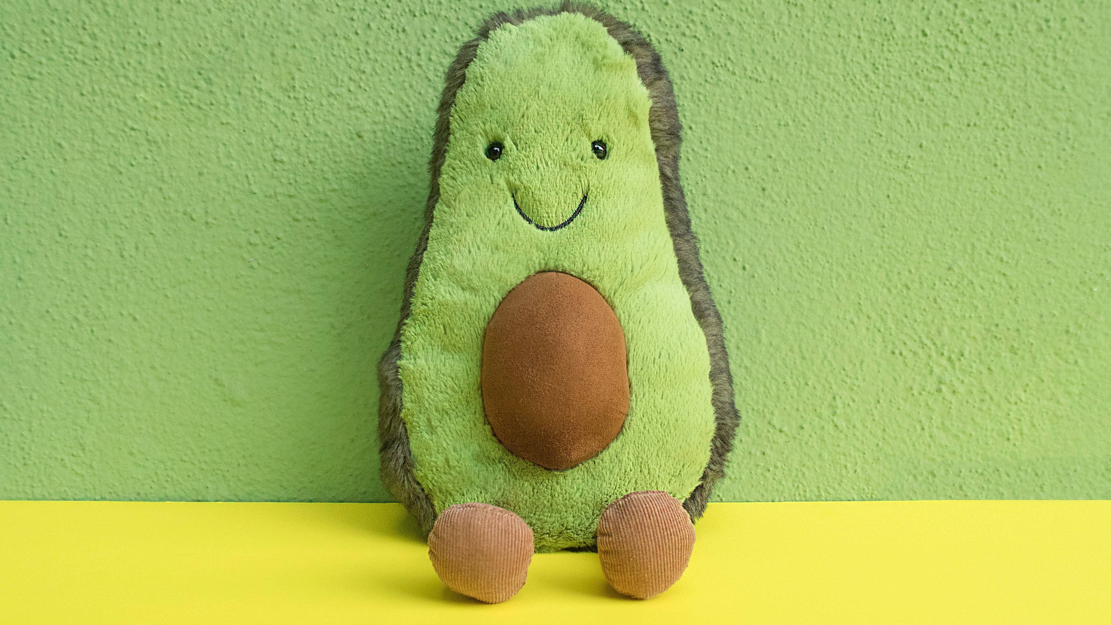 Juguete de aguacate de peluche sobre verde pastel Fondos de pantalla