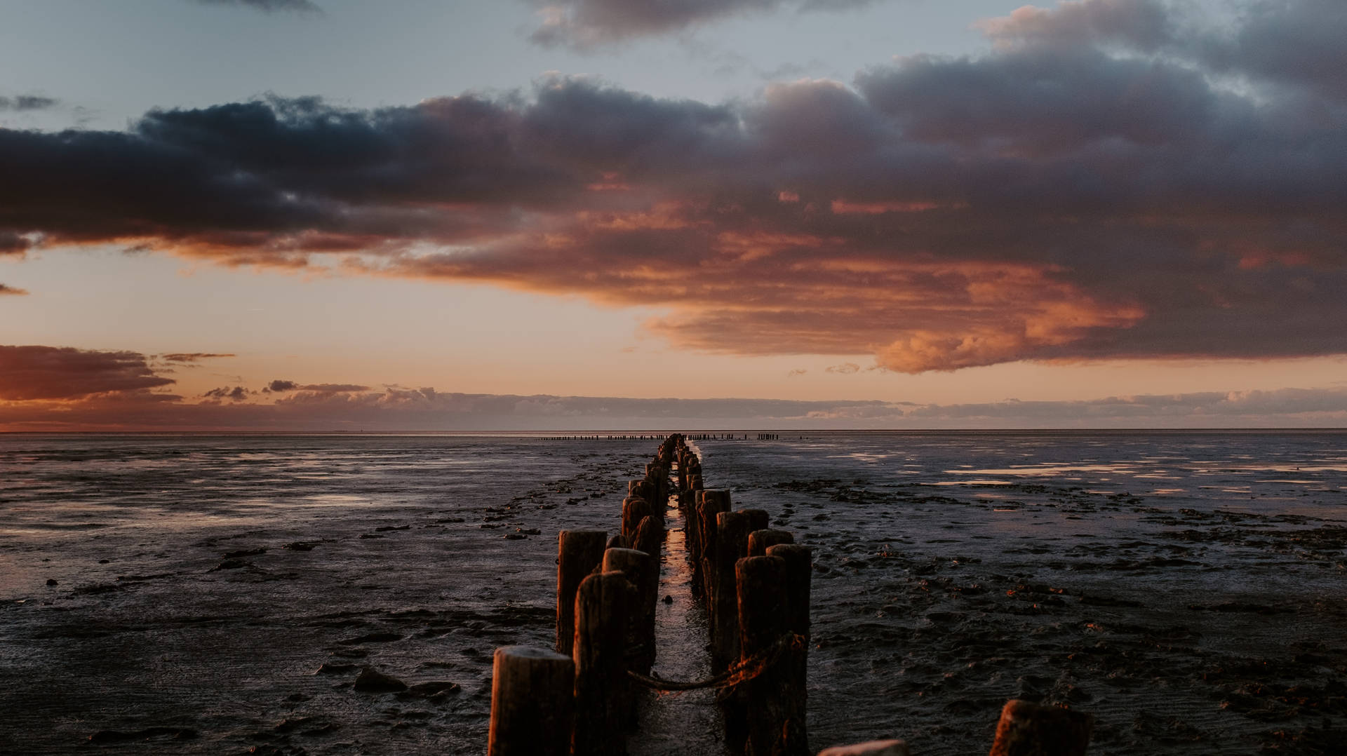 Atardecer en el océano con cielo oscuro, ambiente previo al horizonte vespertino en un muelle.