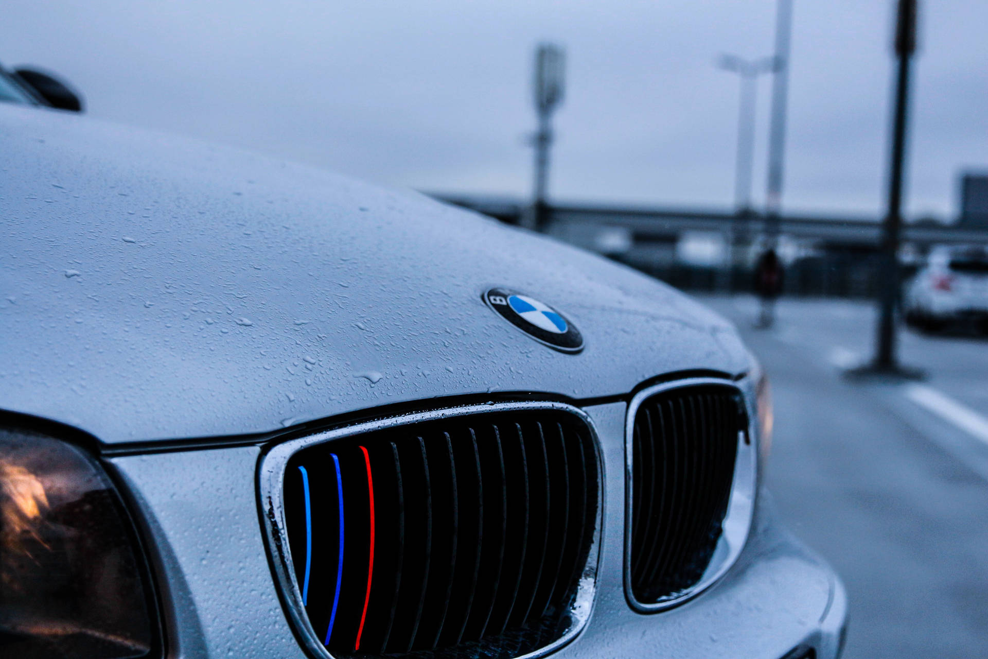 Fondo de pantalla en primer plano del cofre de un BMW blanco con gotas de lluvia