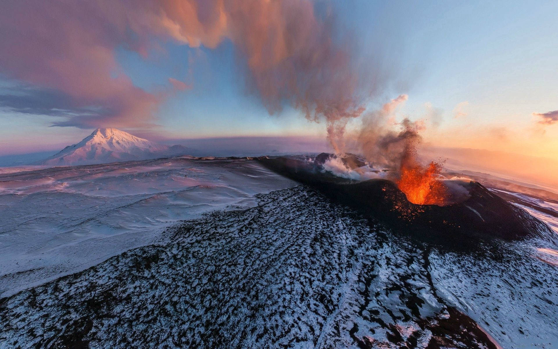Volcano releasing smoke and fire during sunset.