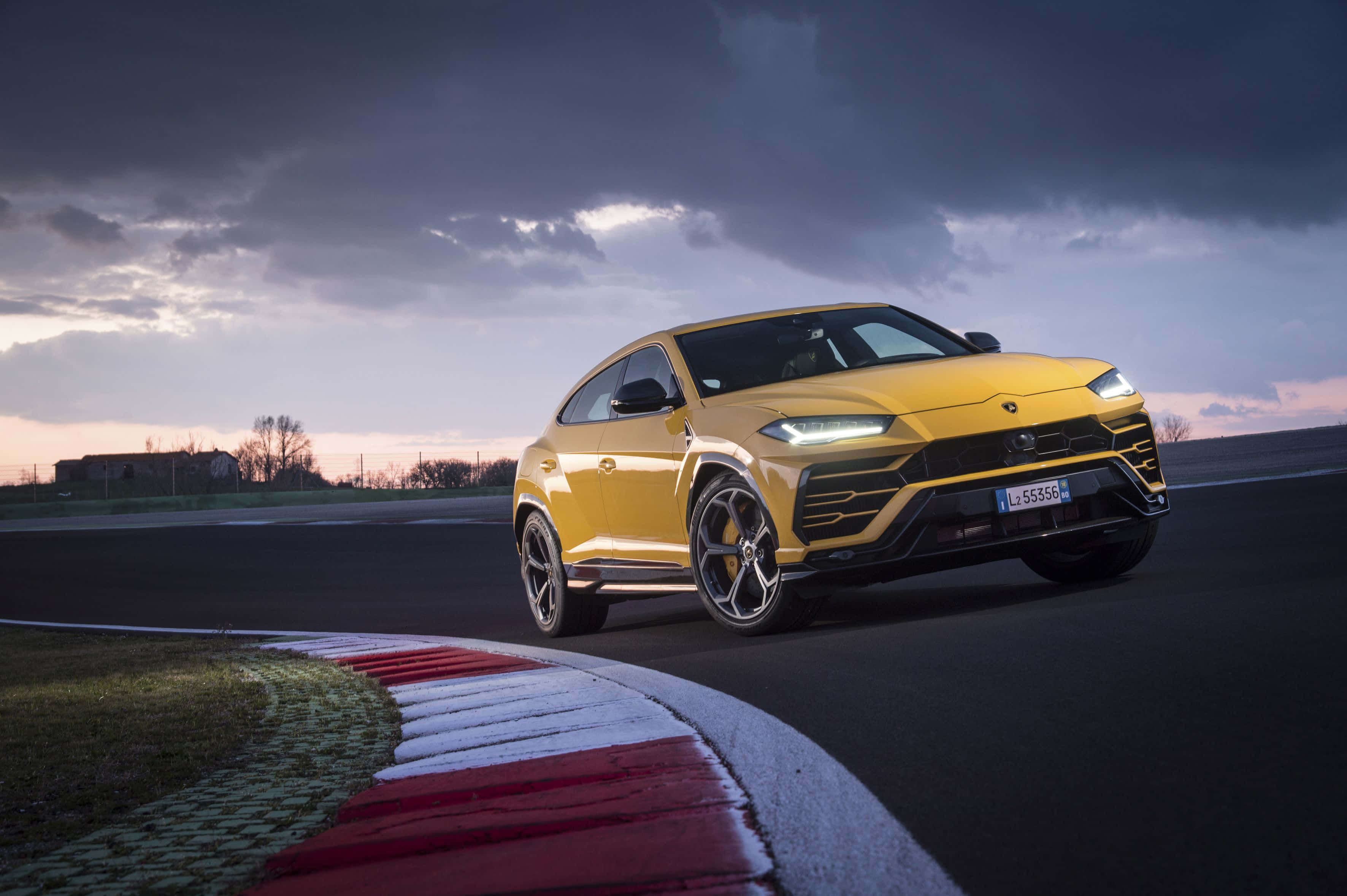 Lamborghini Urus - un SUV amarillo conduciendo en una pista Fondos de pantalla