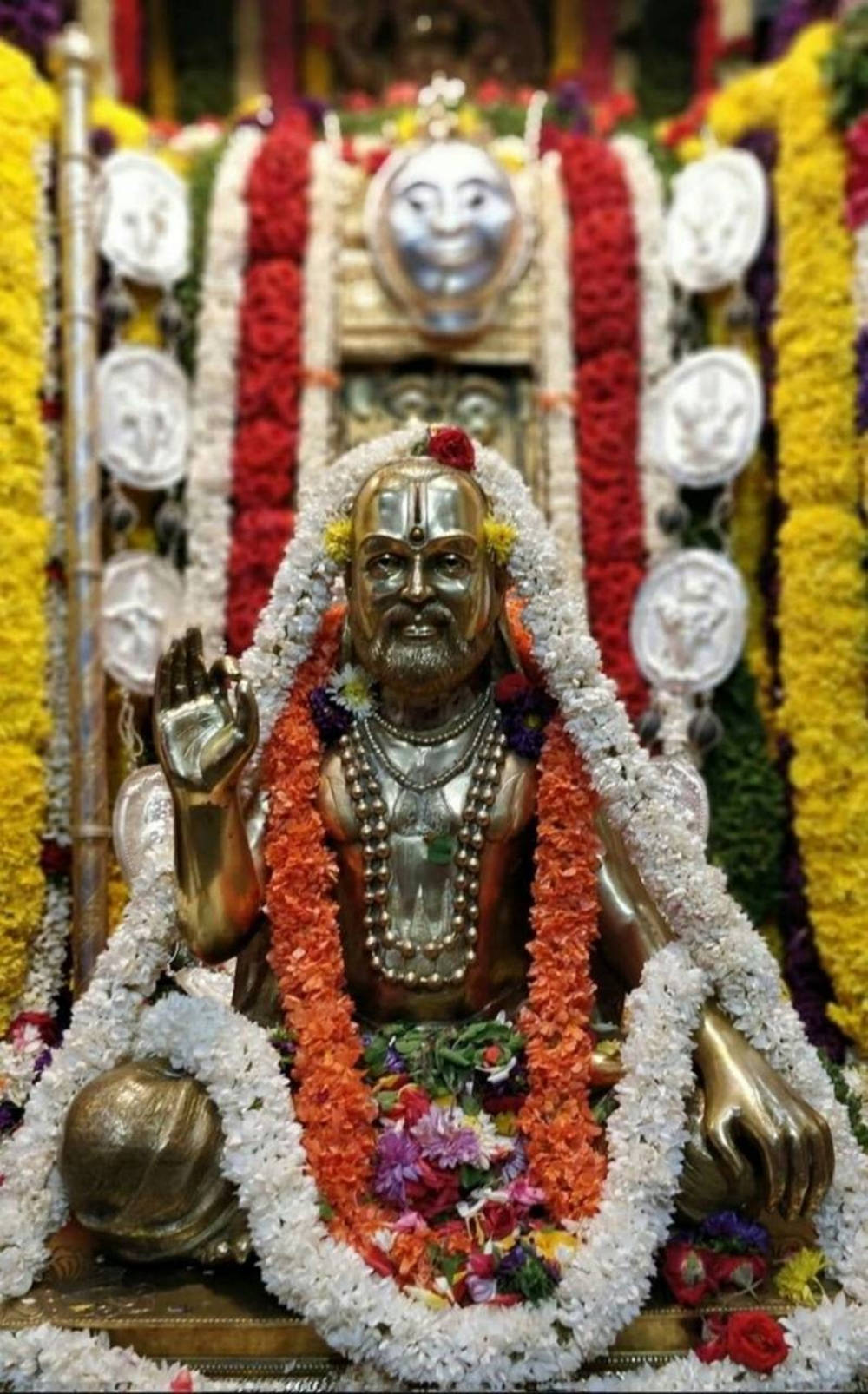 Majestuosa Estatua Dorada de Raghavendra Adornada con Guirnaldas Florales Fondos de pantalla