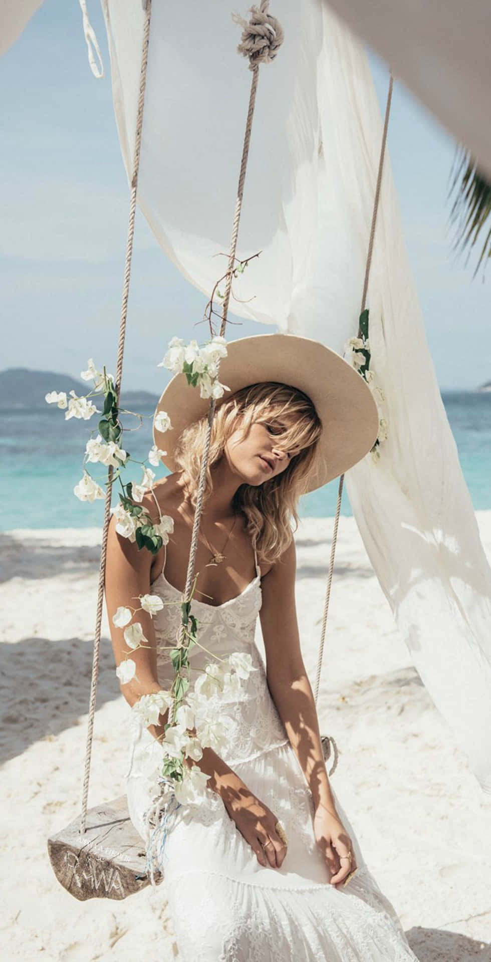 Mujer con vestido blanco sentada en un columpio en la playa Fondos de pantalla