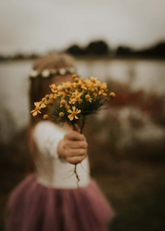 Niña con emociones sosteniendo flores amarillas Fondos de pantalla