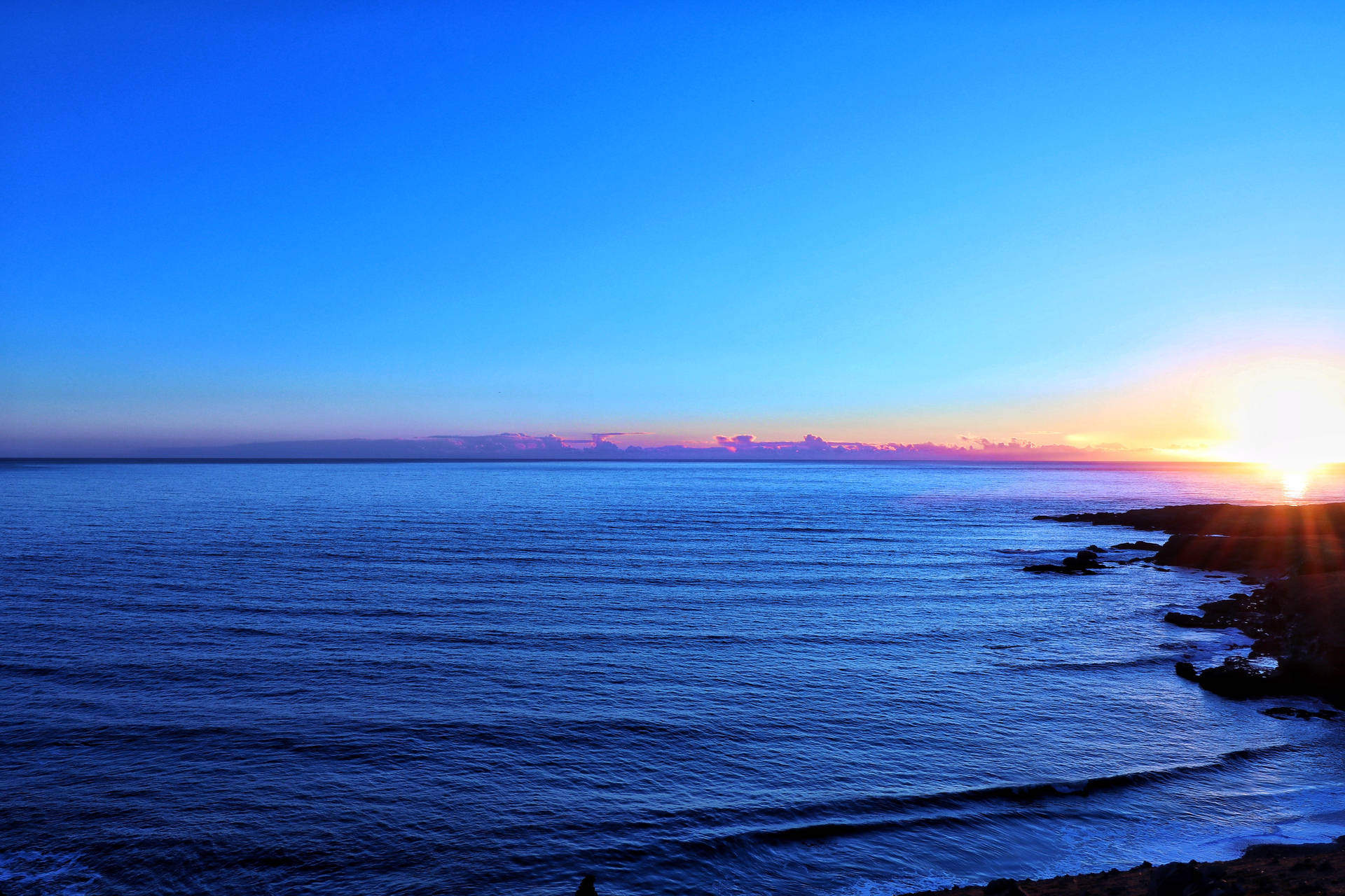Océano azul y cielo mostrando el horizonte durante el atardecer.