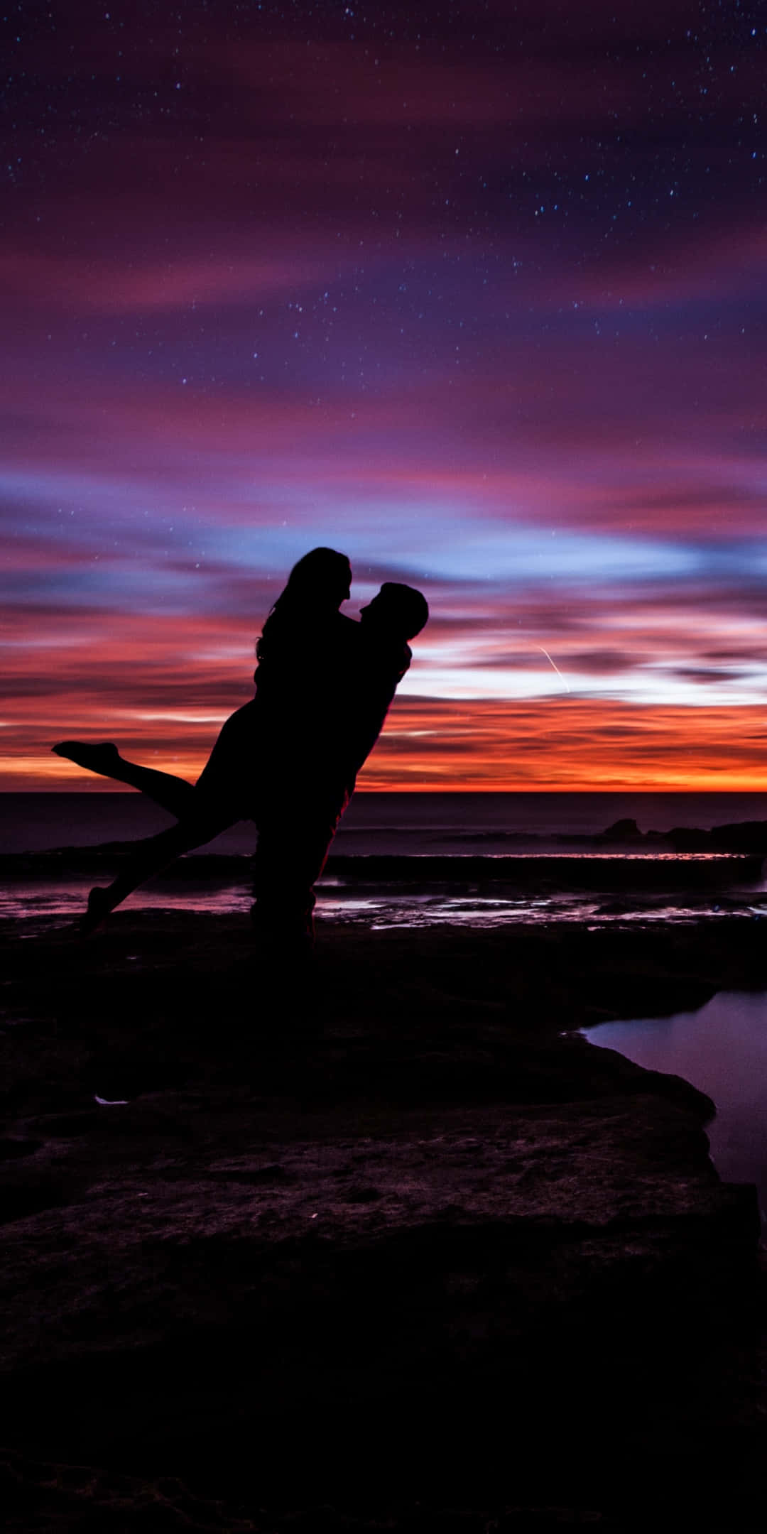 Pareja al atardecer bajo el cielo púrpura cargando a la mujer Fondos de pantalla