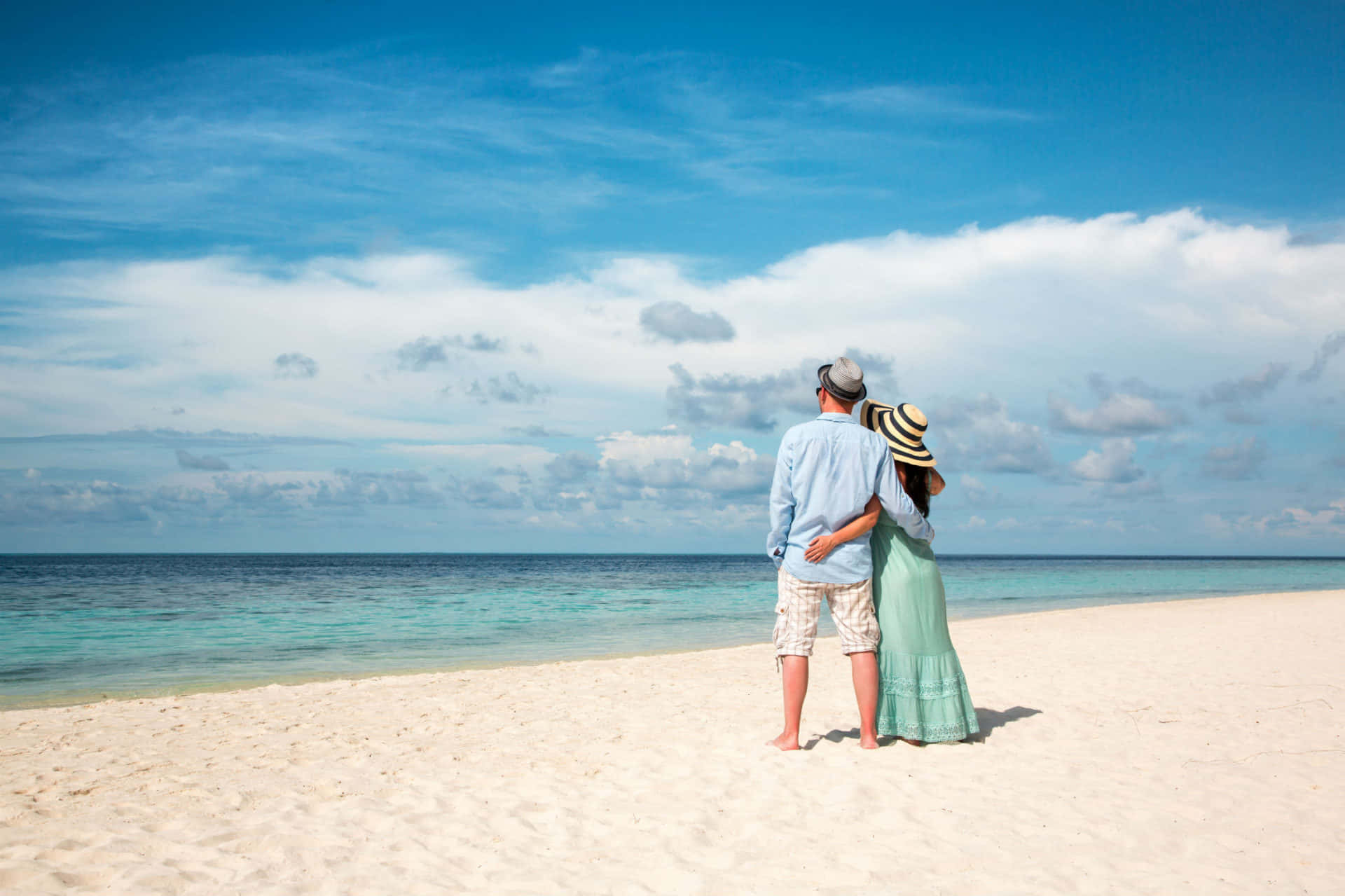 Pareja en la playa bajo el cielo azul Fondos de pantalla