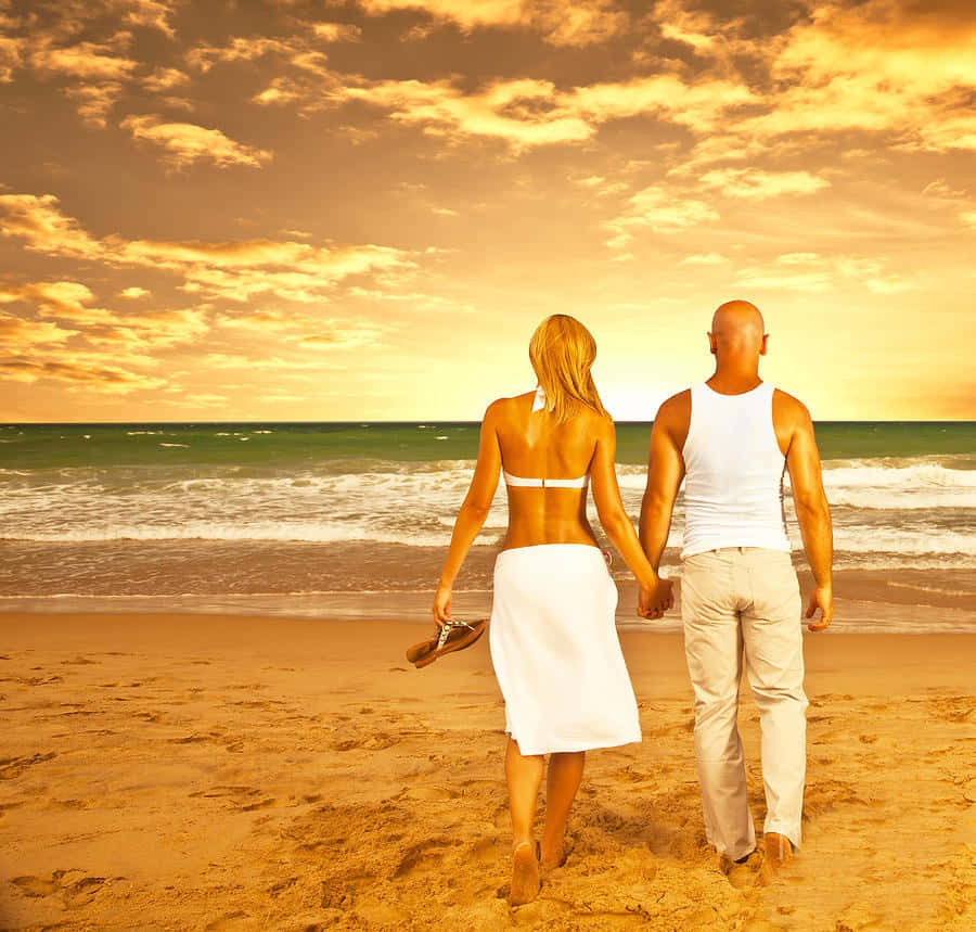 Pareja en la playa bajo un cielo naranja Fondos de pantalla