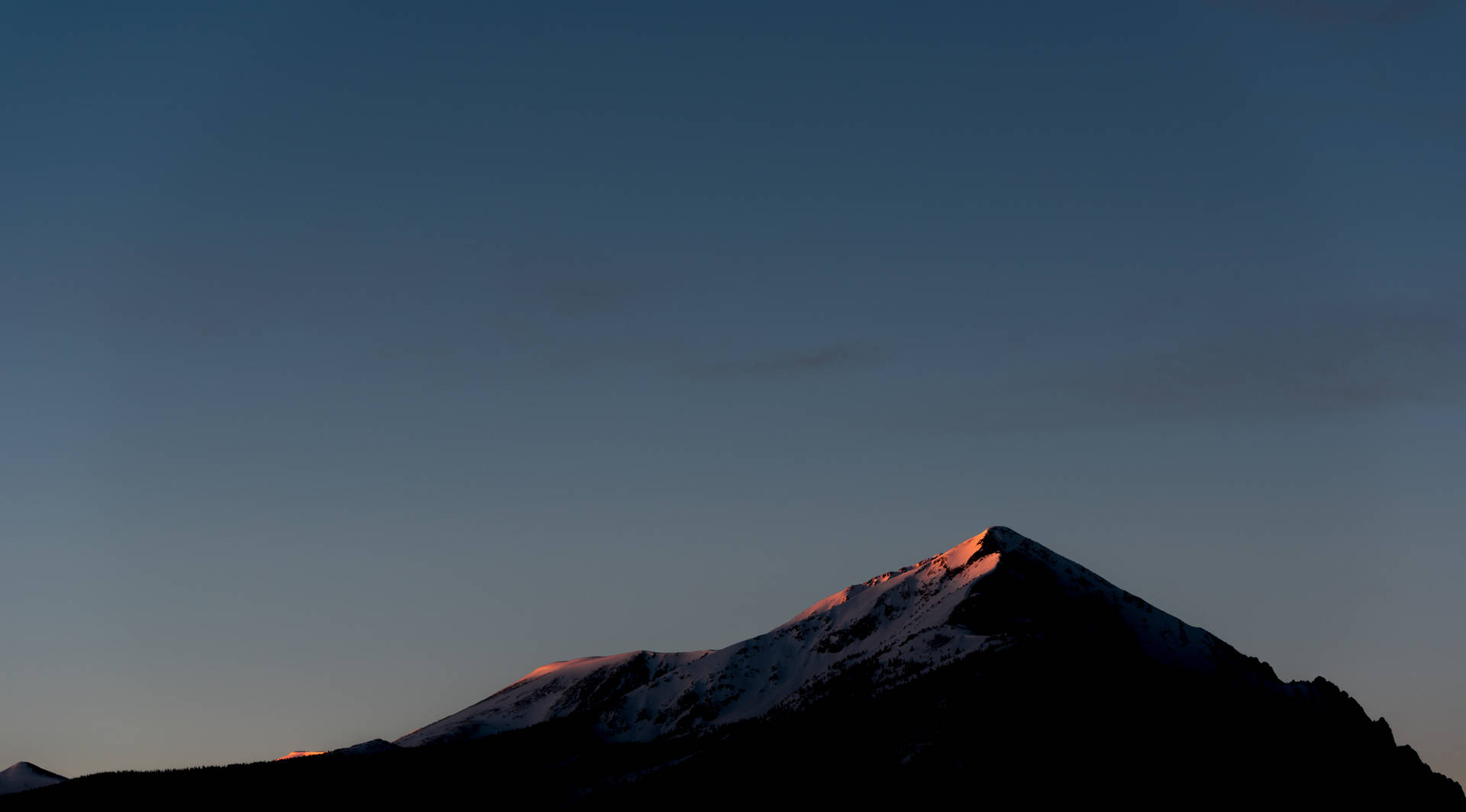 Cima de montaña con sombra y cielo despejado antes de la noche.