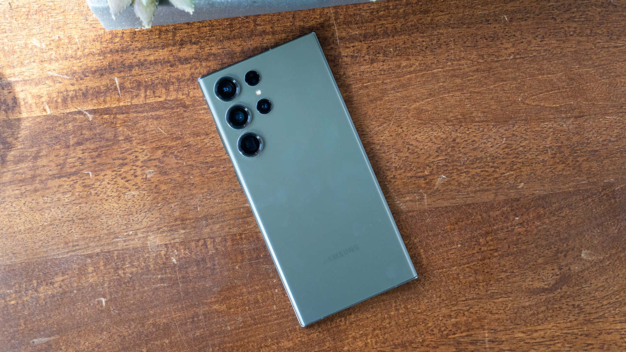 Samsung S23 Ultra verde trasero con conjunto de cámaras sobre superficie de madera Fondos de pantalla