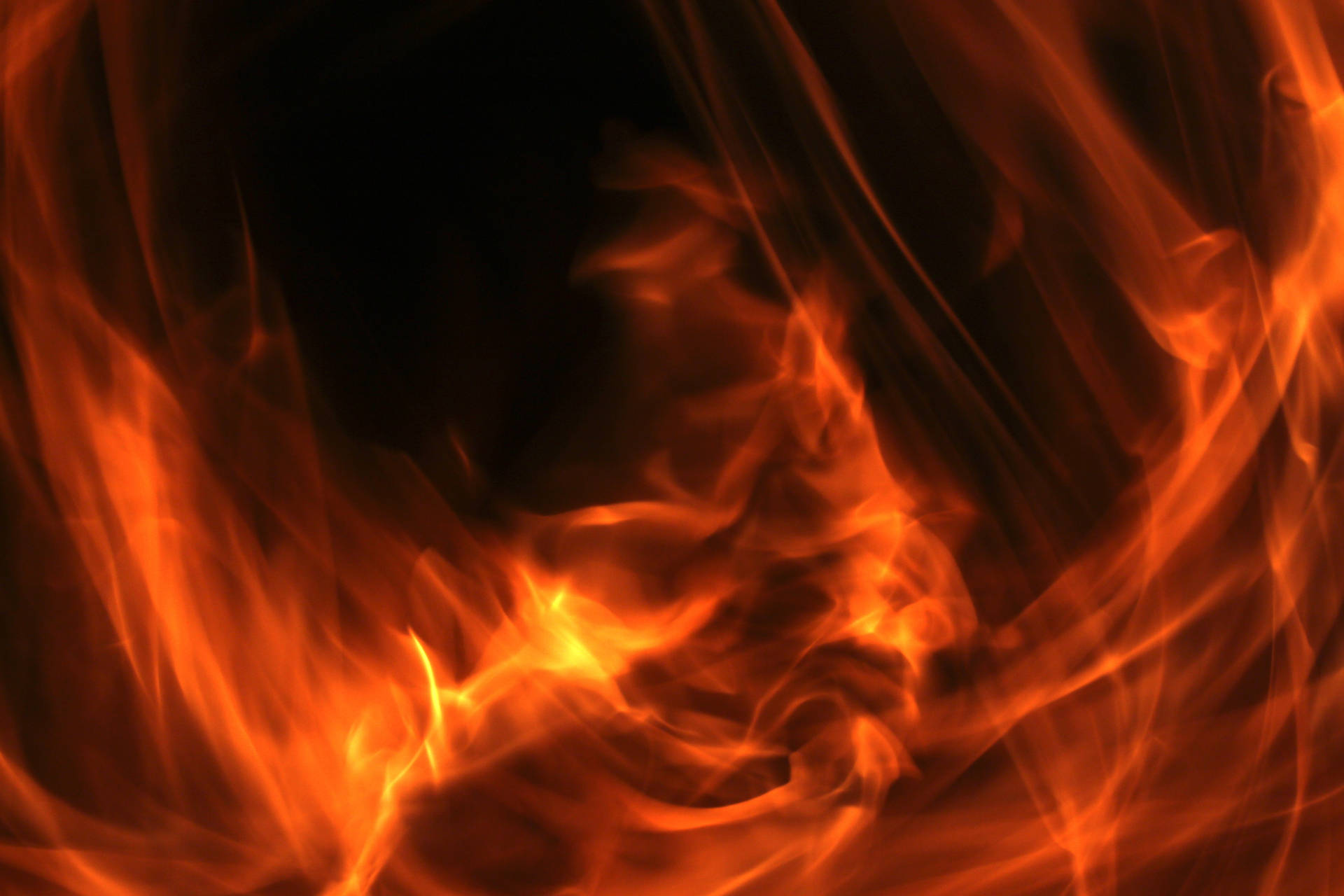 Fuego ardiente con llamas rojo anaranjadas sobre un fondo negro.