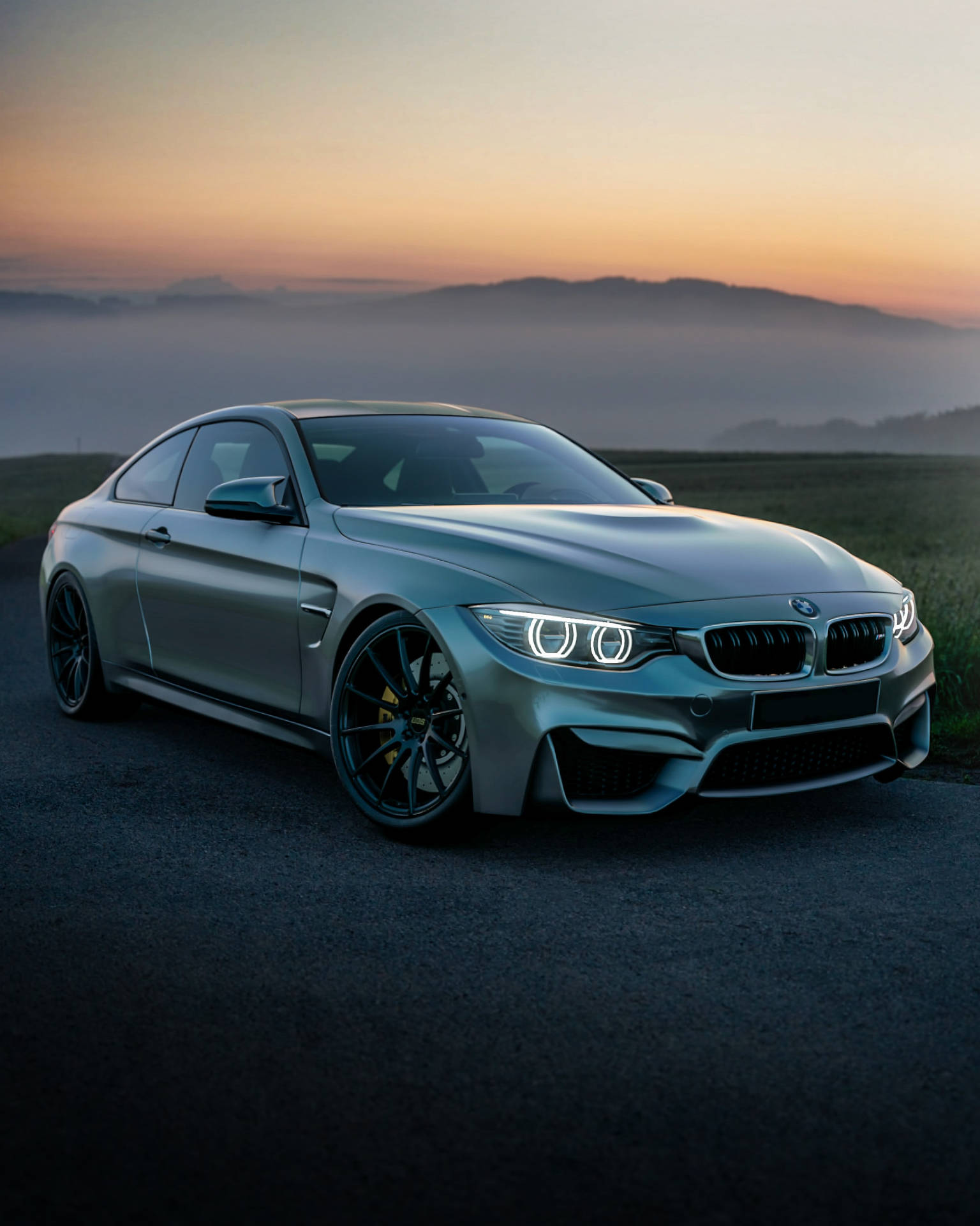 Fondo de pantalla de un BMW F83 M4 gris en una montaña al amanecer