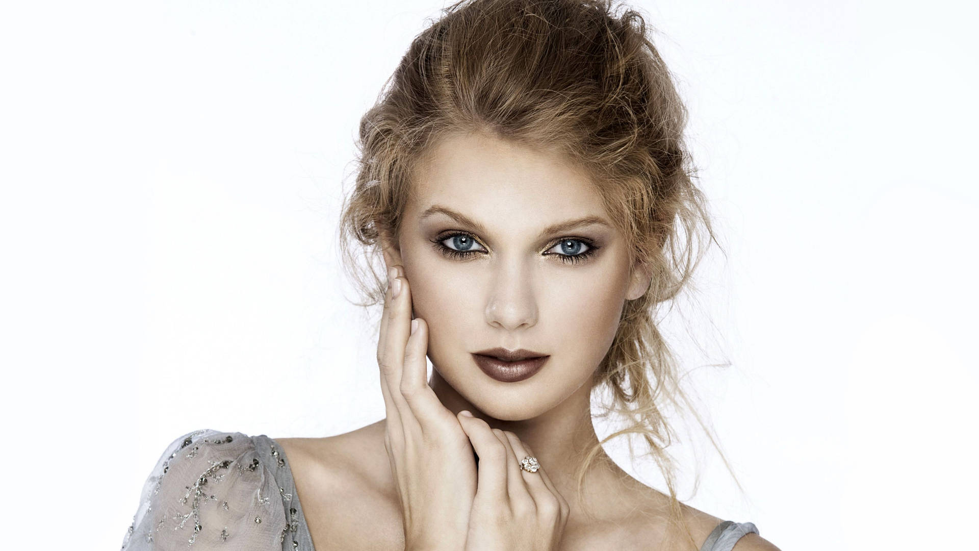 Fondo de pantalla de Taylor Swift con maquillaje nude y moño despeinado.