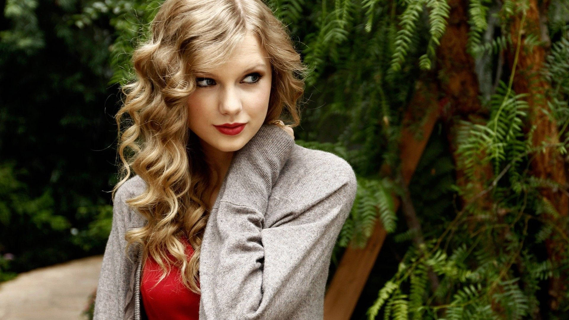 Linda foto de fondo de pantalla de Taylor Swift con rizos y pose de mirada lateral.