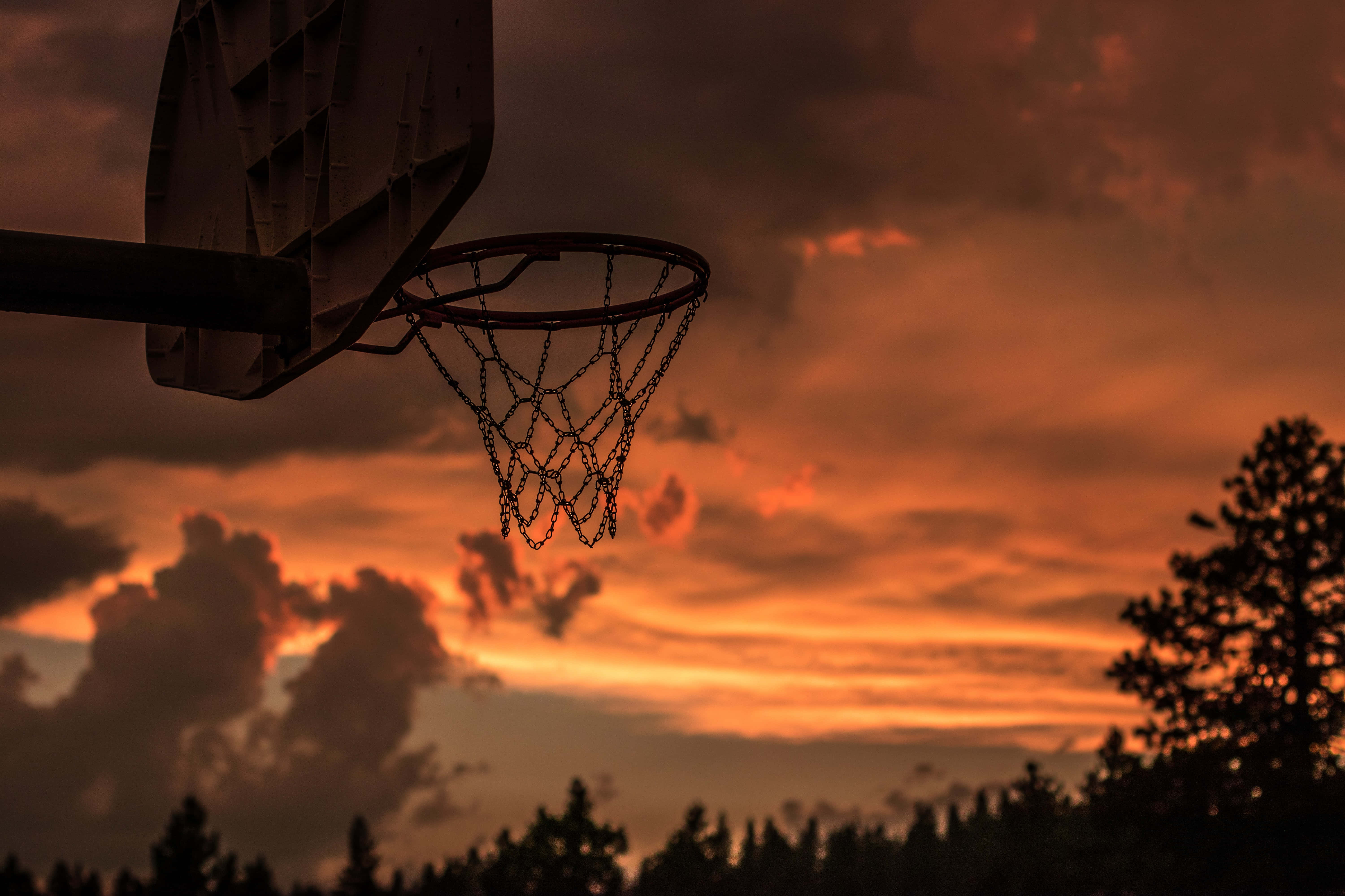 un aro de baloncesto con un cielo al atardecer detrás Fondos de pantalla