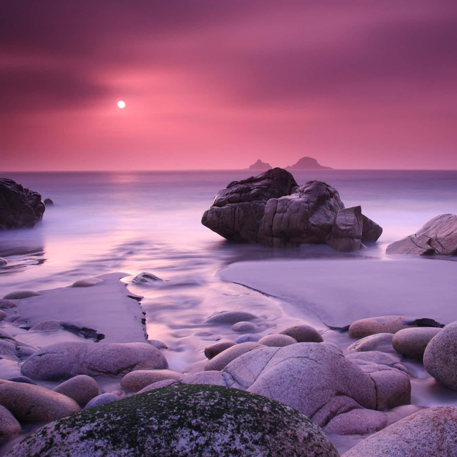 Un atardecer rosa sobre rocas y agua Fondos de pantalla