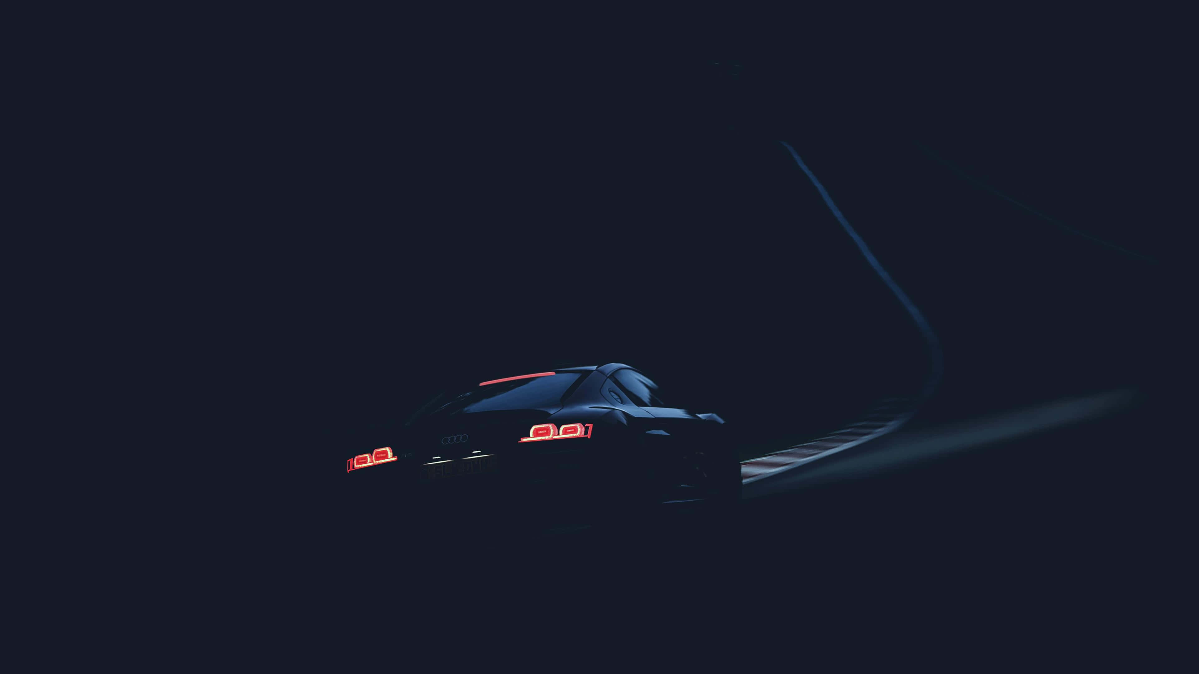 un auto conduciendo por una carretera oscura Fondos de pantalla