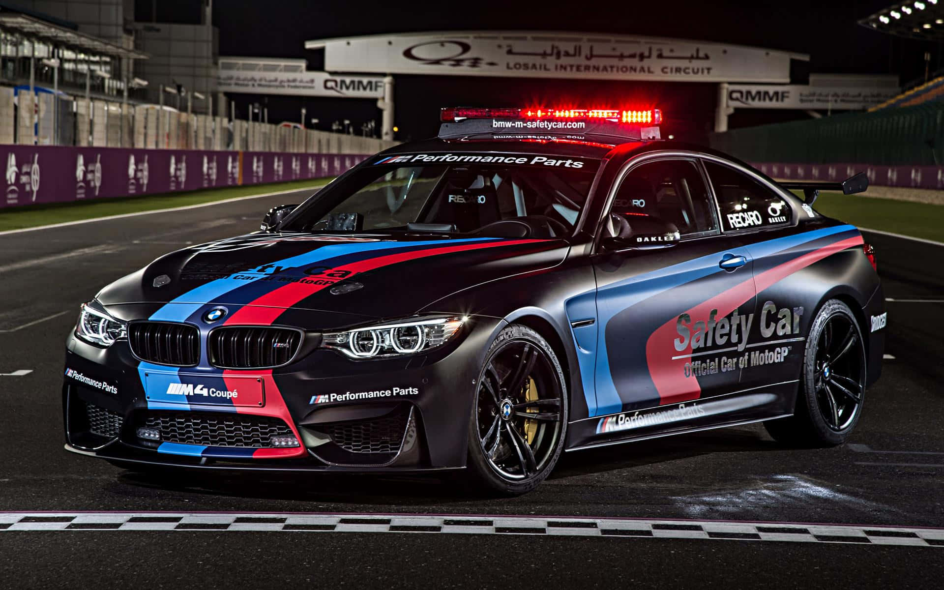 Un auto de seguridad moderno y elegante liderando la carrera en la pista Fondos de pantalla
