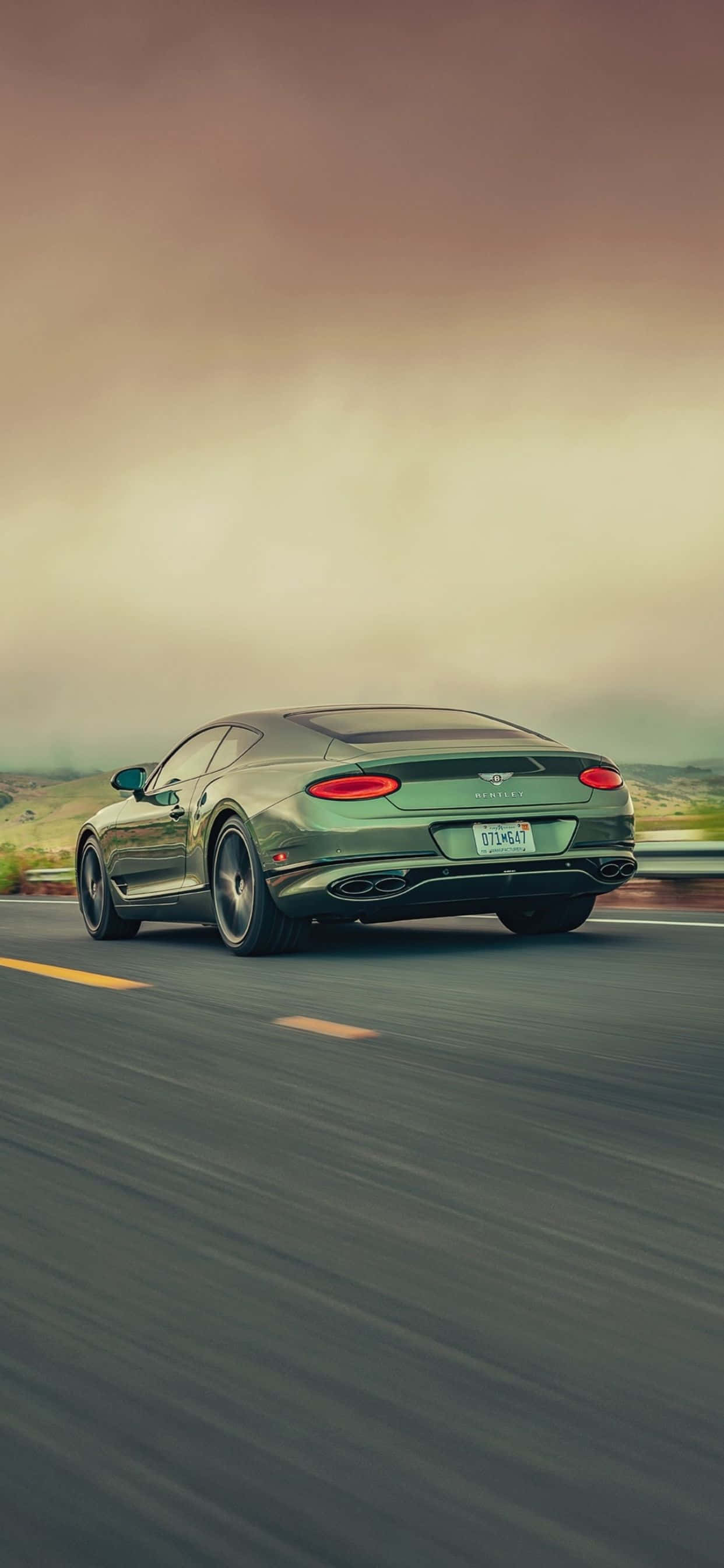 un auto verde conduciendo por una carretera con cielo nublado Fondos de pantalla