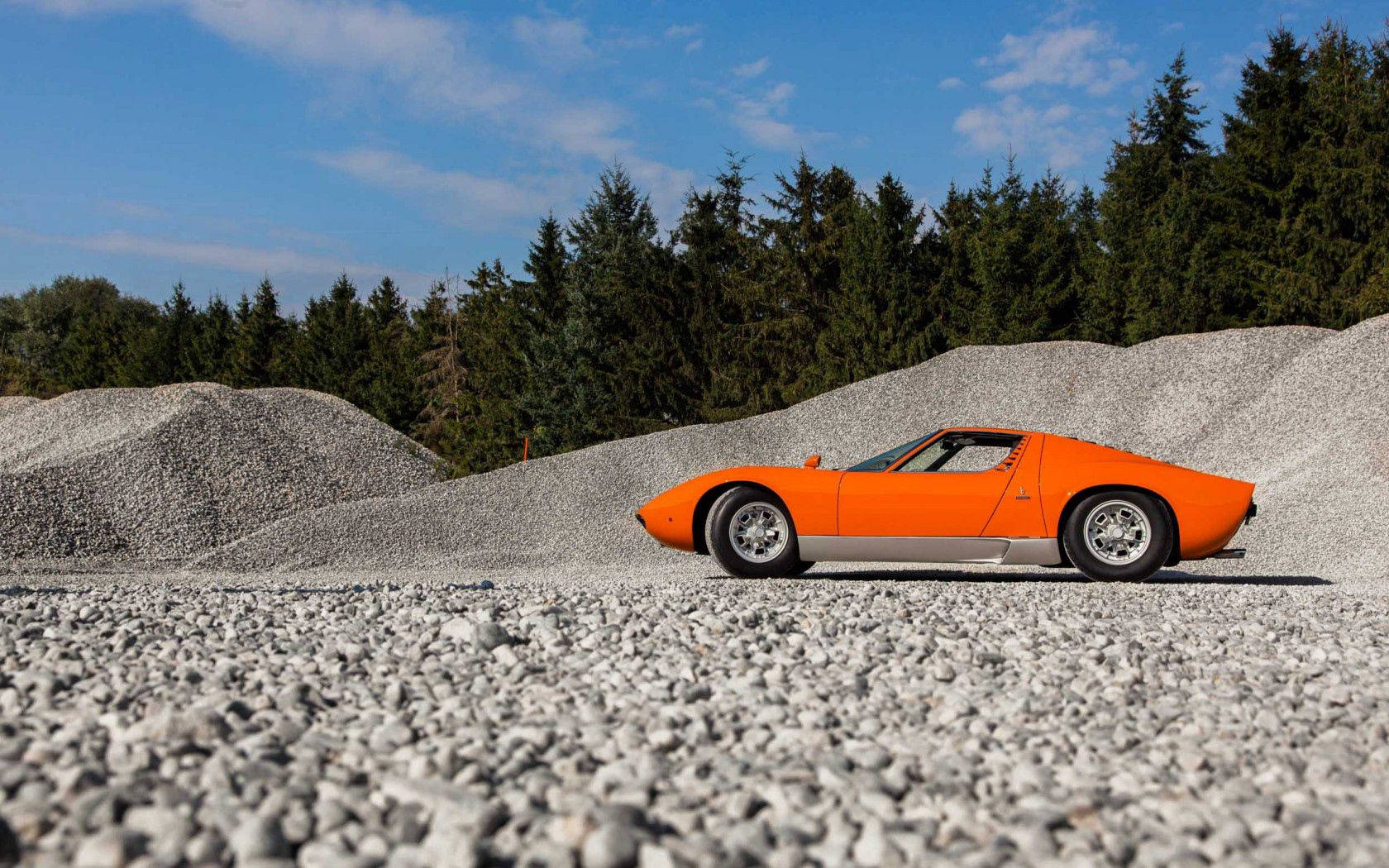 Fondo de pantalla de Lamborghini Miura naranja en grava.