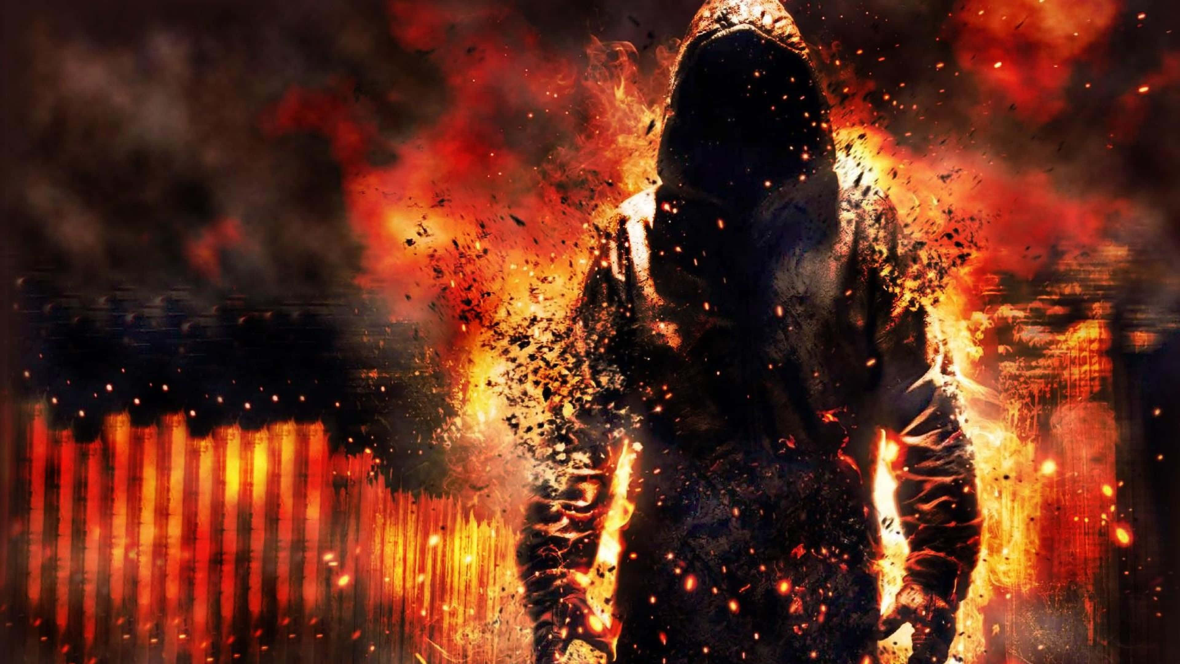 Un hombre con sudadera con capucha frente al fuego Fondos de pantalla