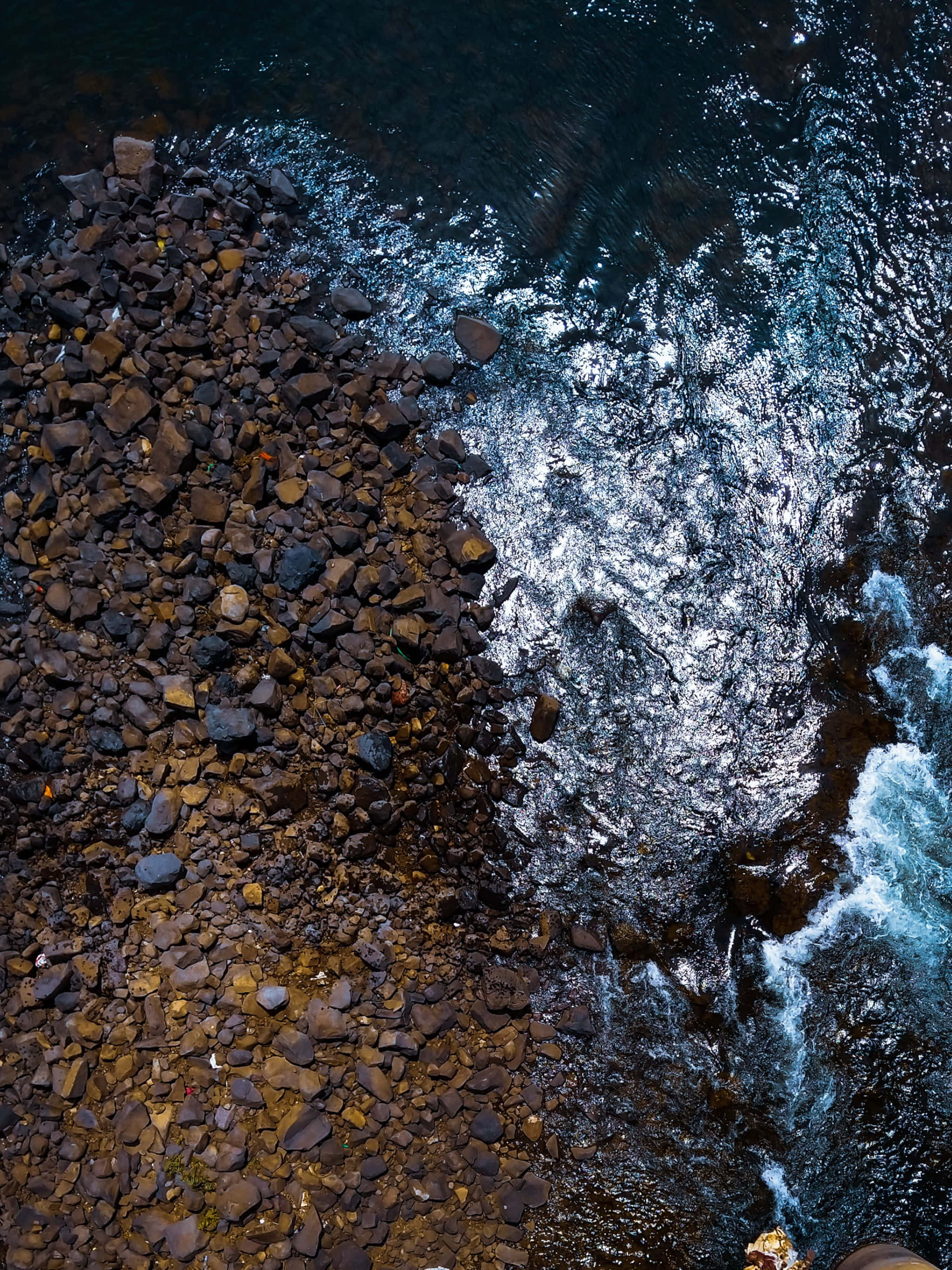 un hombre está de pie en un acantilado con vista al agua Fondos de pantalla