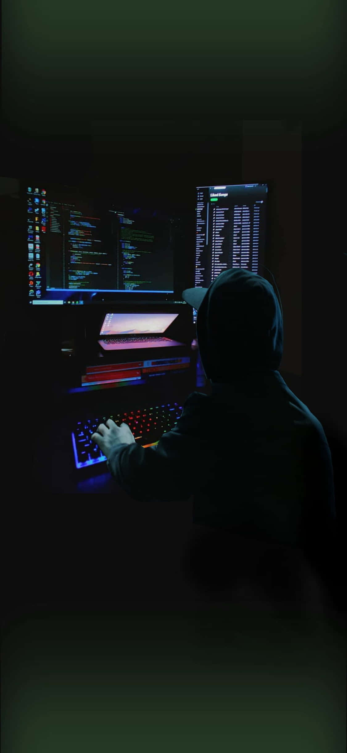 un hombre sentado frente a una computadora en la oscuridad Fondos de pantalla