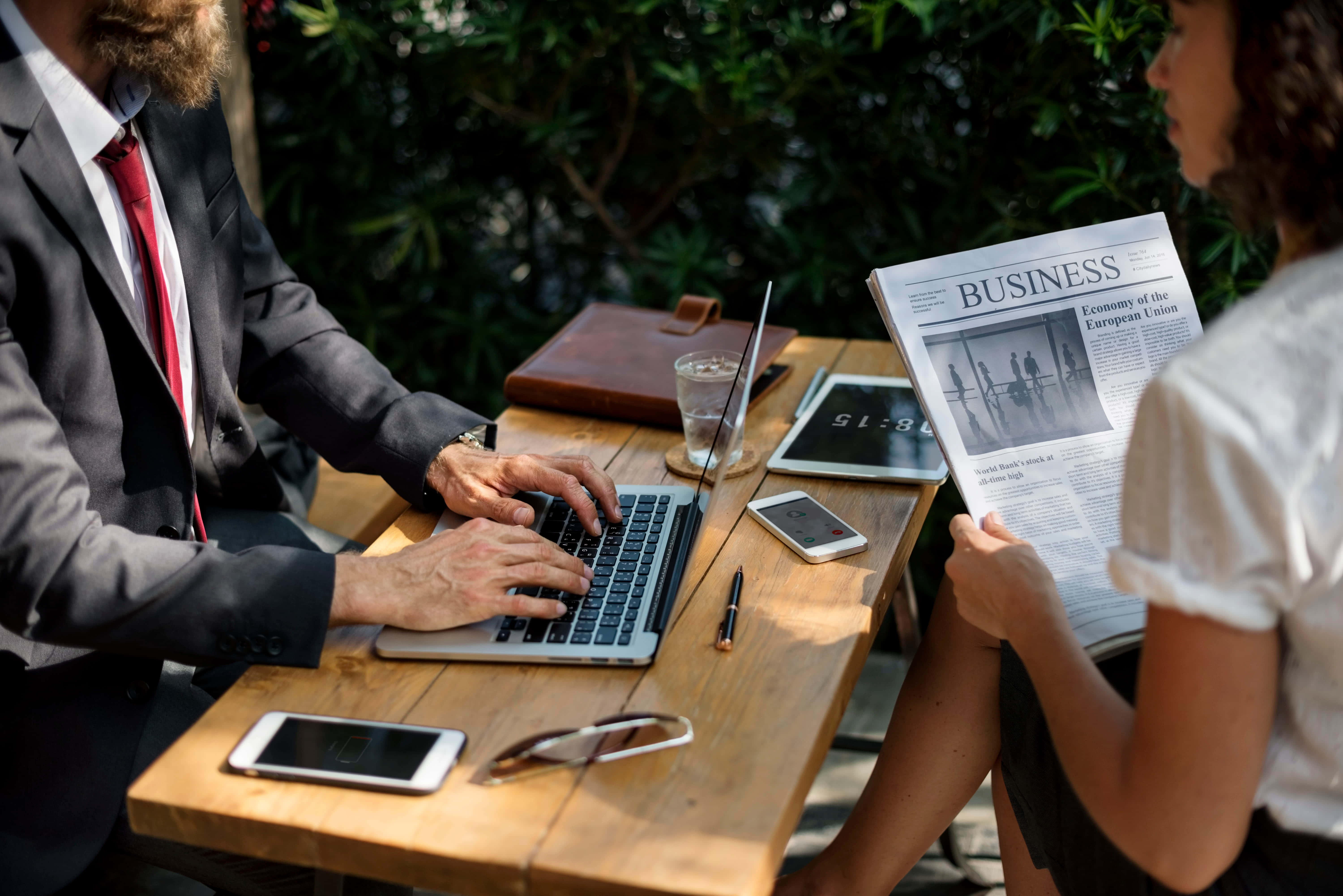 un hombre y una mujer de negocios sentados en una mesa usando una laptop Fondos de pantalla