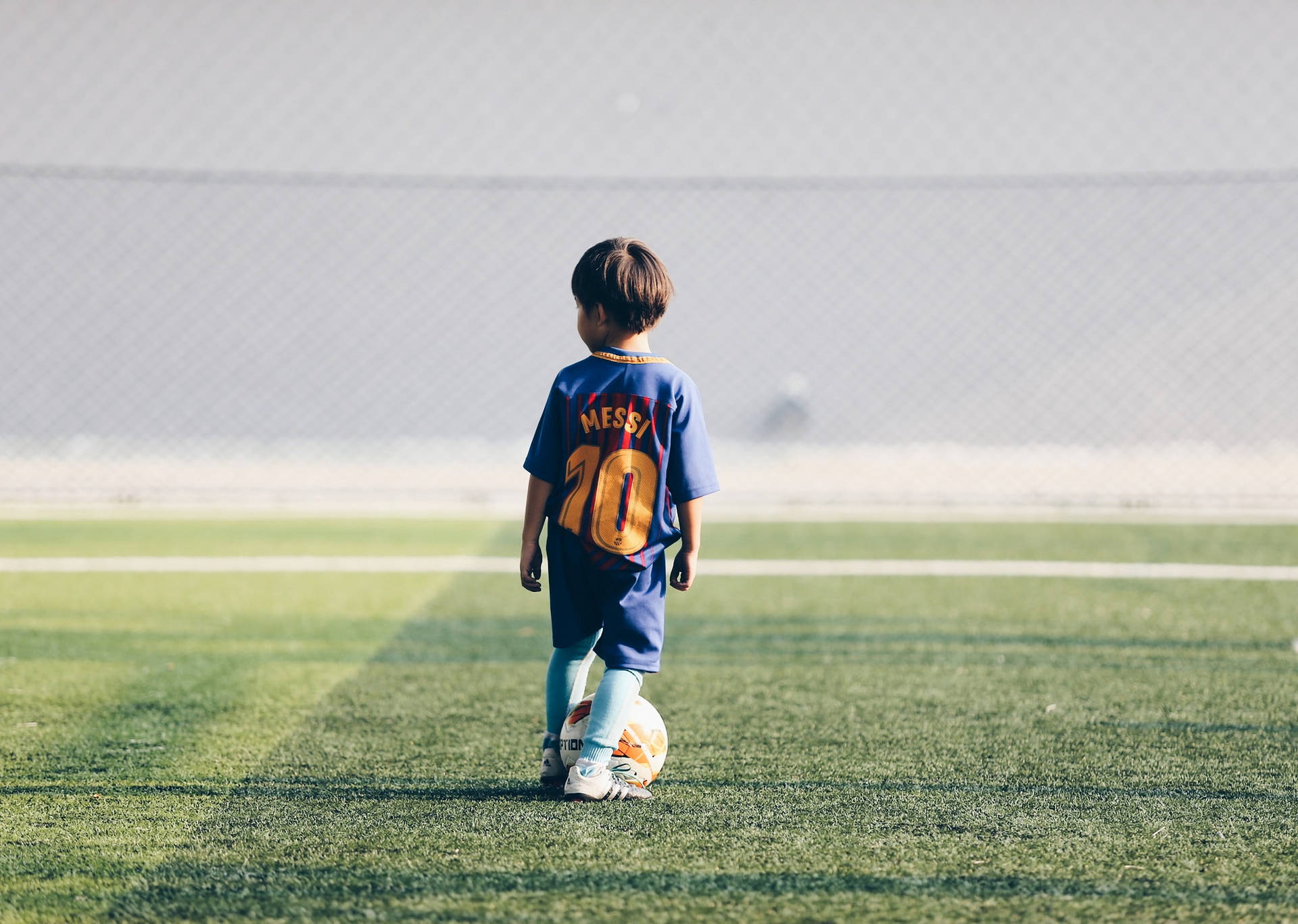 Fondo de pantalla de escritorio de niño aficionado al fútbol con camiseta de Lionel Messi.