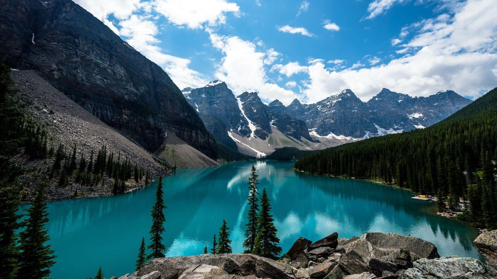 Un lago azul rodeado de montañas y árboles Fondos de pantalla