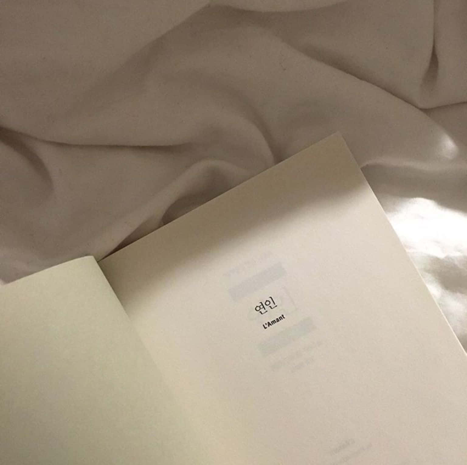 un libro con portada blanca sobre una cama Fondos de pantalla