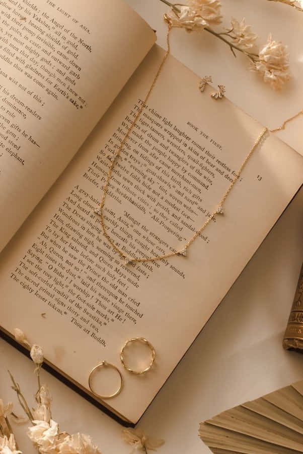 Un libro con un collar y un anillo sobre él Fondos de pantalla