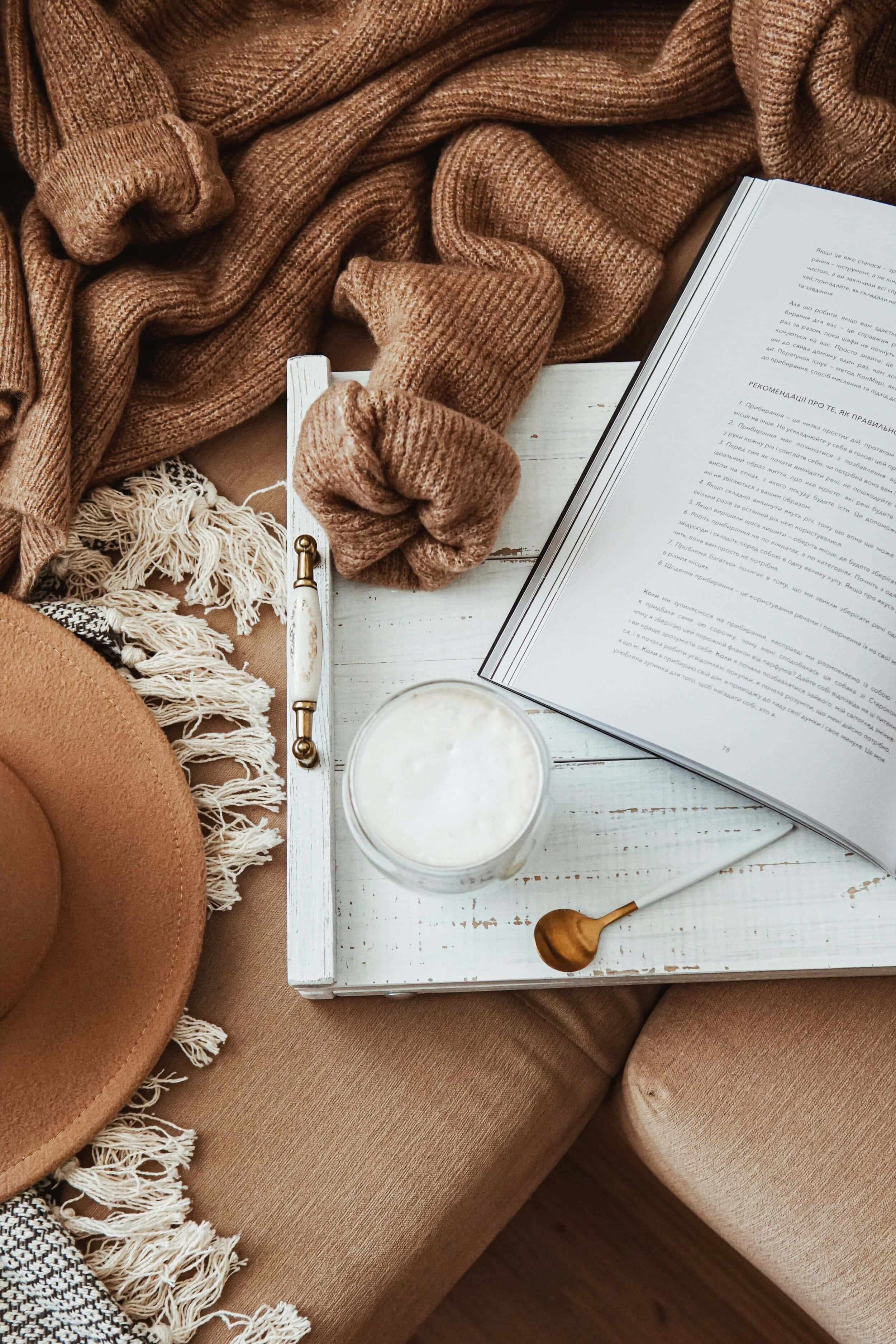 Un libro, un sombrero y una taza sobre un sofá Fondos de pantalla