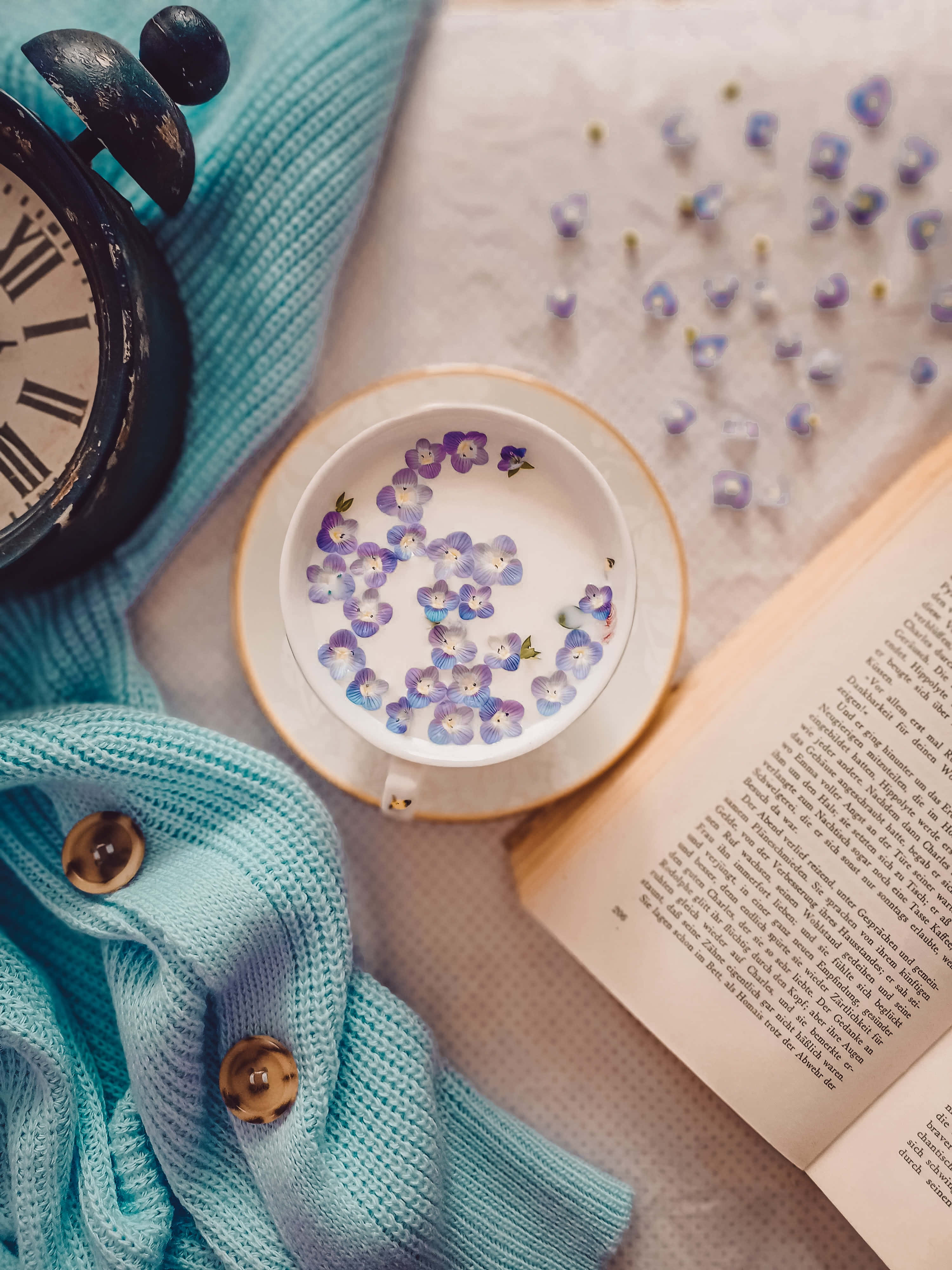 Un libro, una taza de té y un reloj sobre una cama Fondos de pantalla