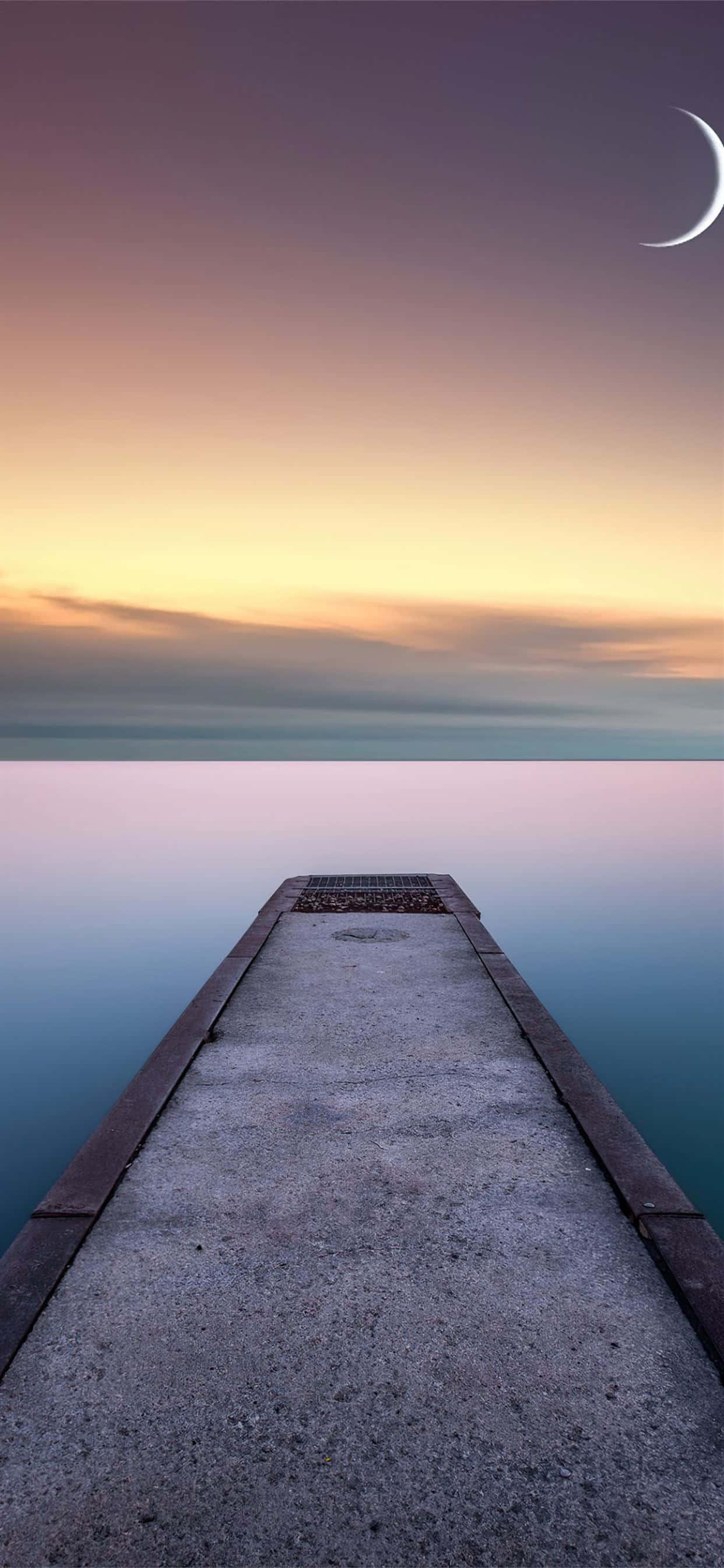 un muelle que lleva al agua con una luna creciente Fondos de pantalla